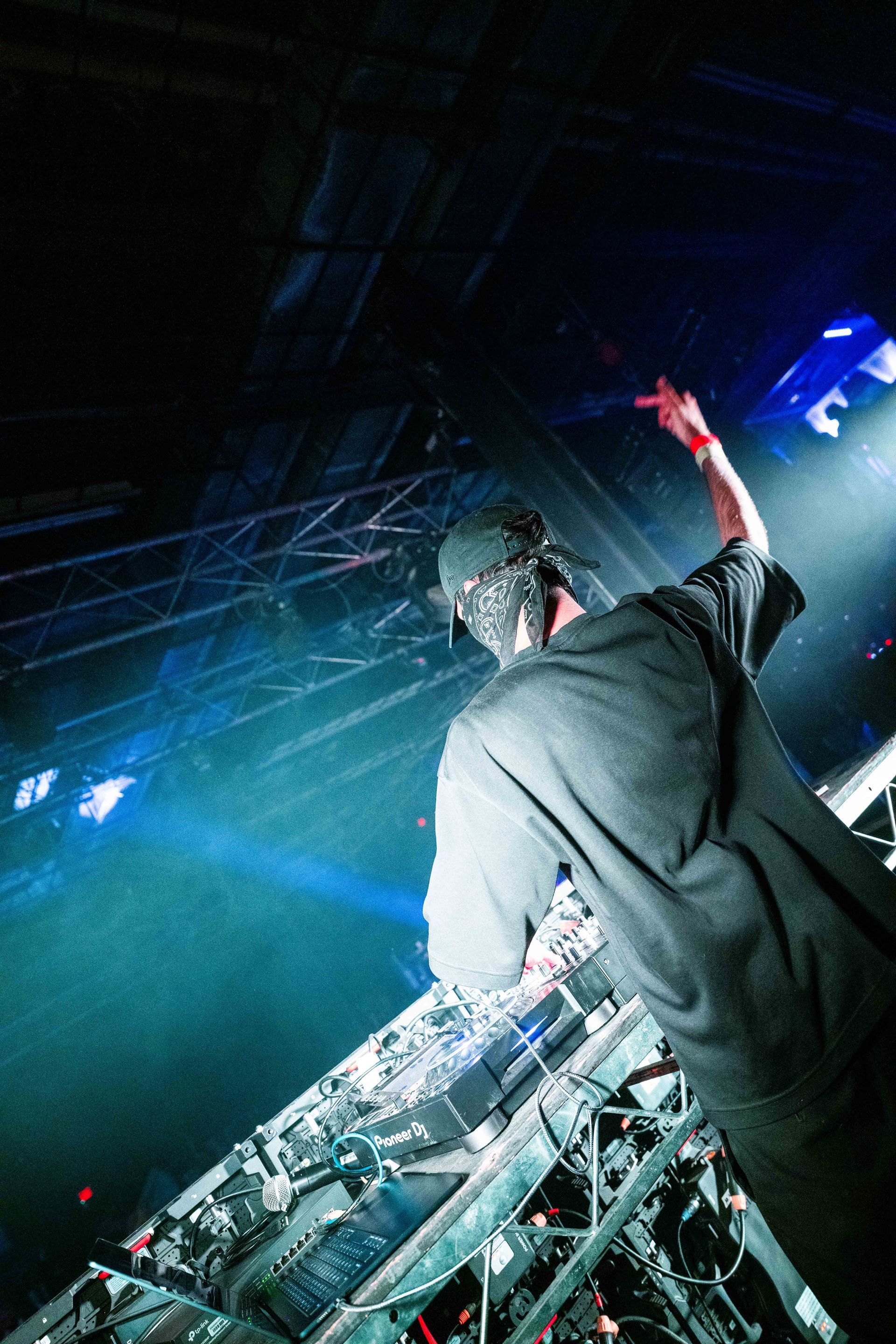 A man is playing a dj set in a dark room.
