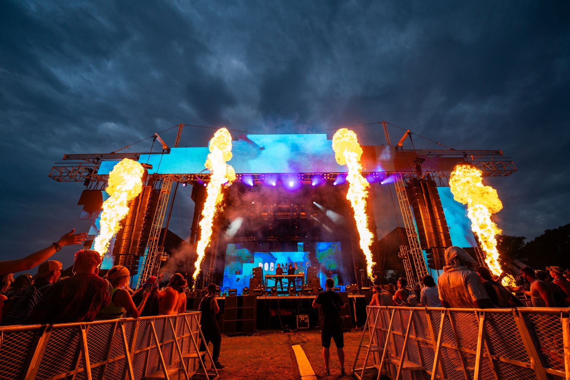 A group of people are standing in front of a stage with flames coming out of it.