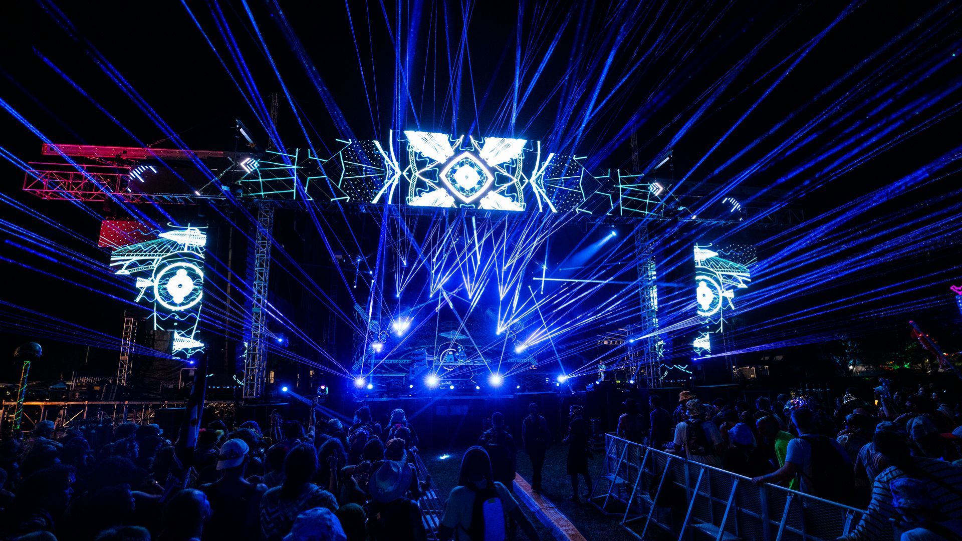 A crowd of people are standing in front of a stage at a concert.