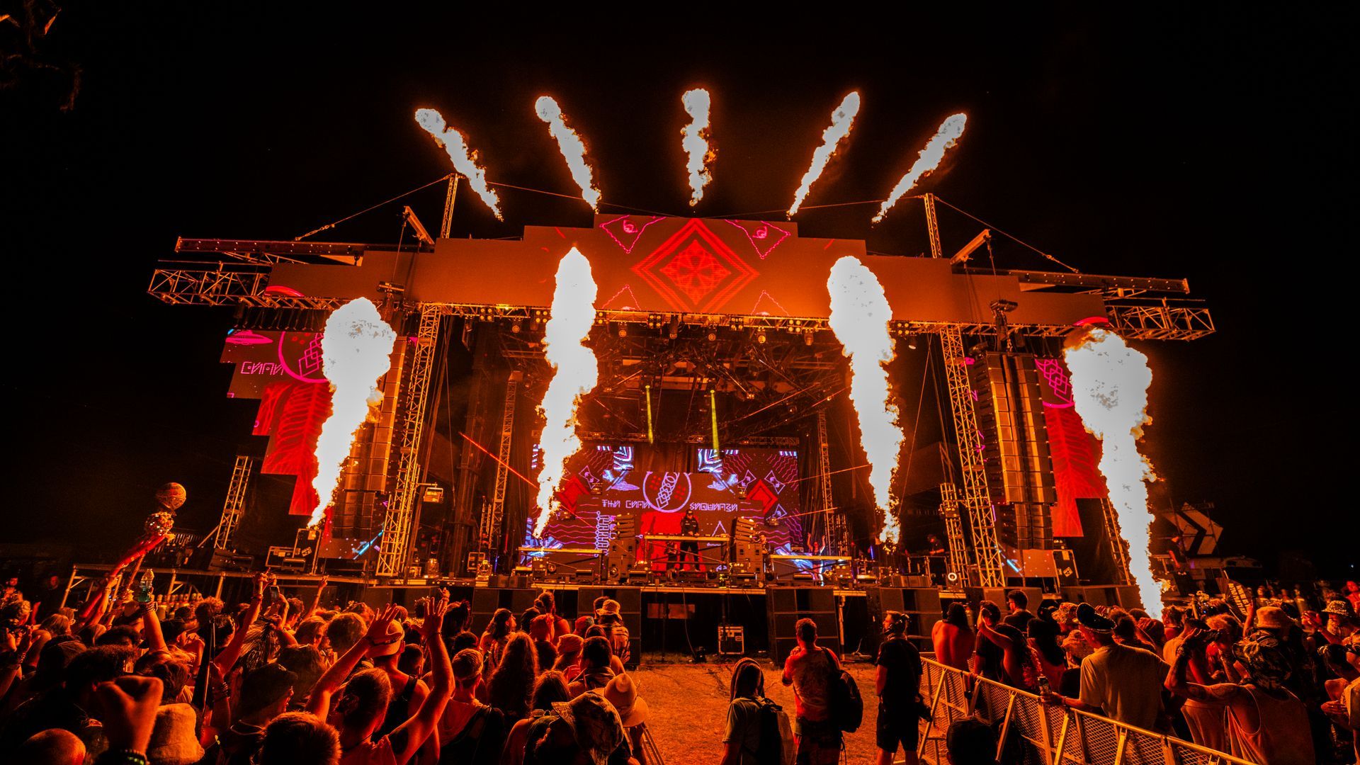 A crowd of people are standing in front of a stage at a concert.