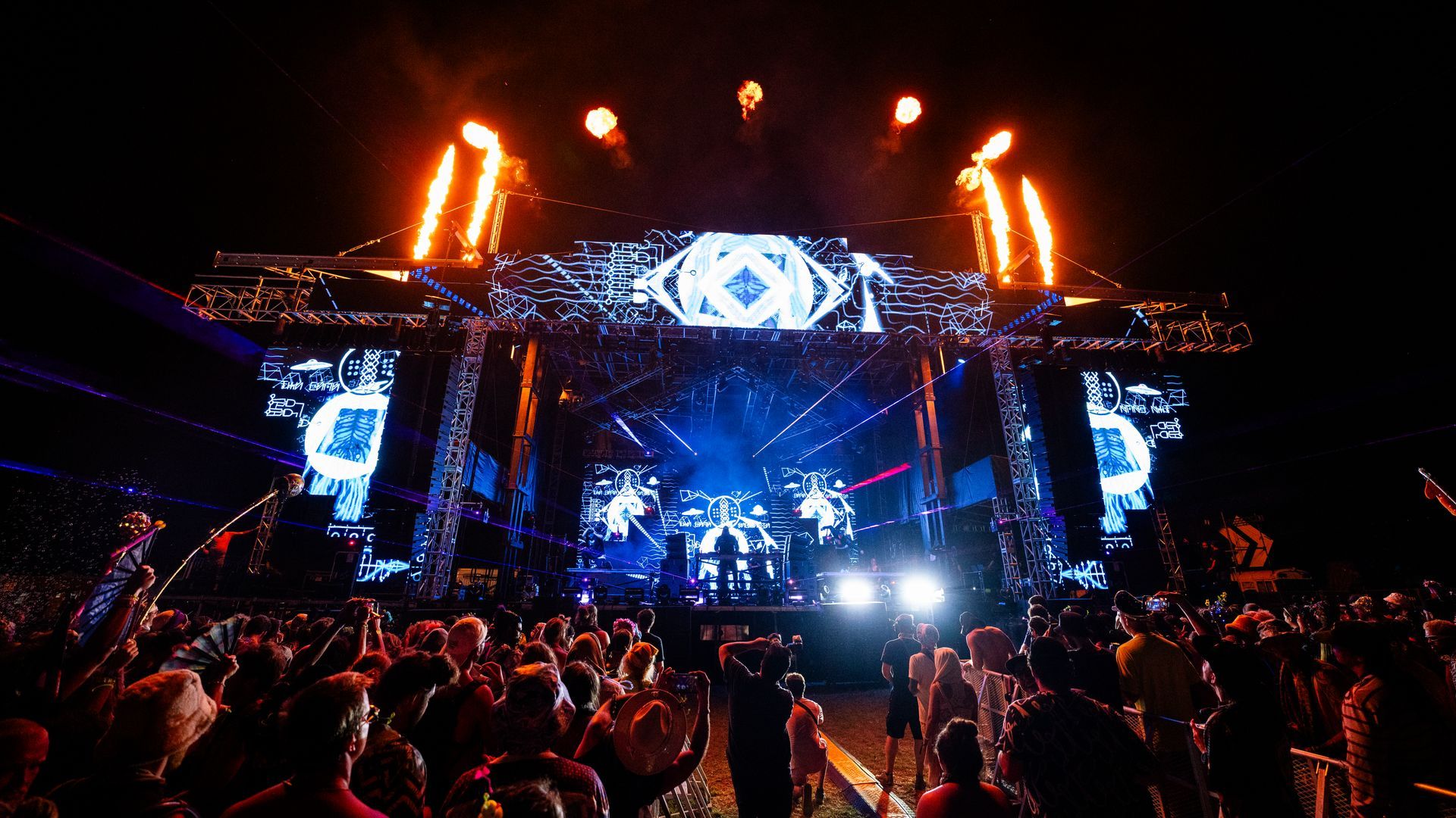 A crowd of people are standing in front of a stage at a concert.