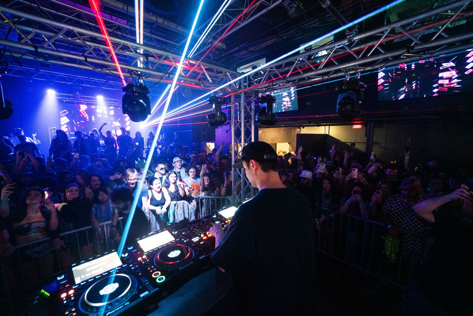 A dj is playing music in front of a crowd at a club.