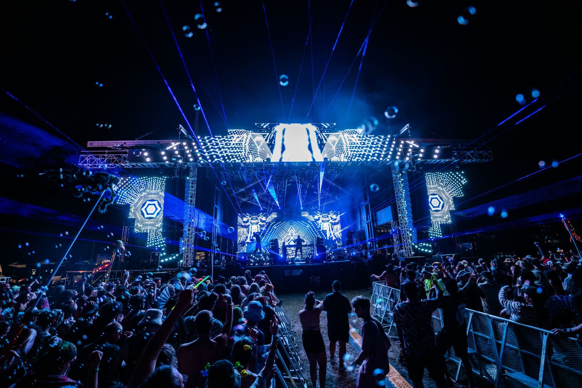 A crowd of people are standing in front of a stage at a concert.
