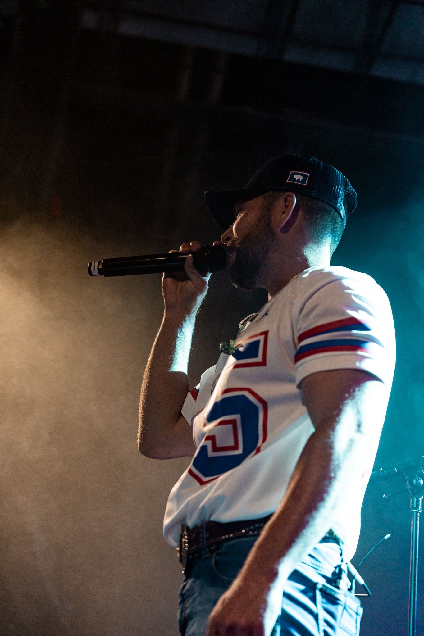 A man in a football jersey is singing into a microphone.