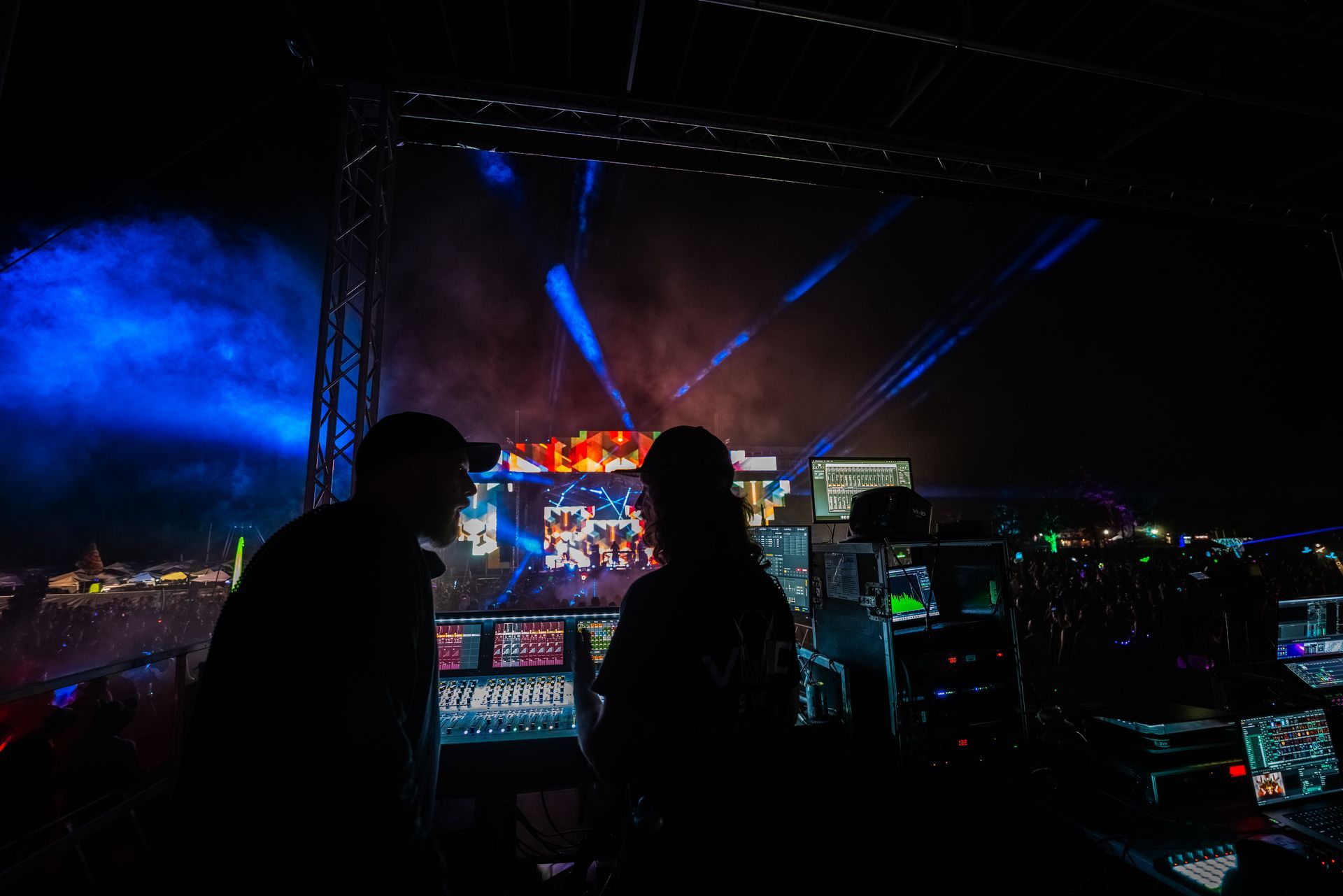 A couple of people standing in front of a stage watching a concert.