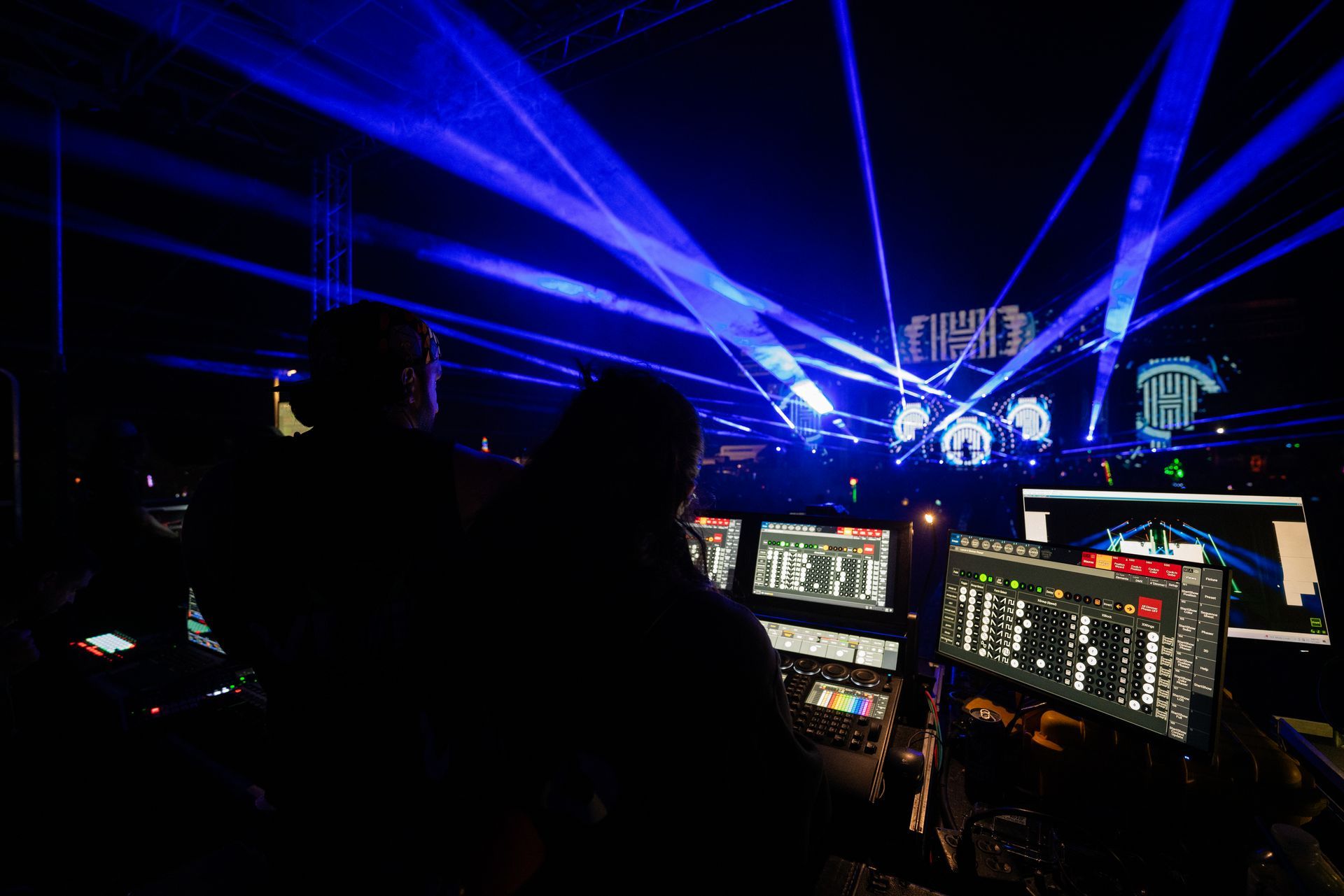 A couple of people standing in front of a stage with blue lights coming out of it