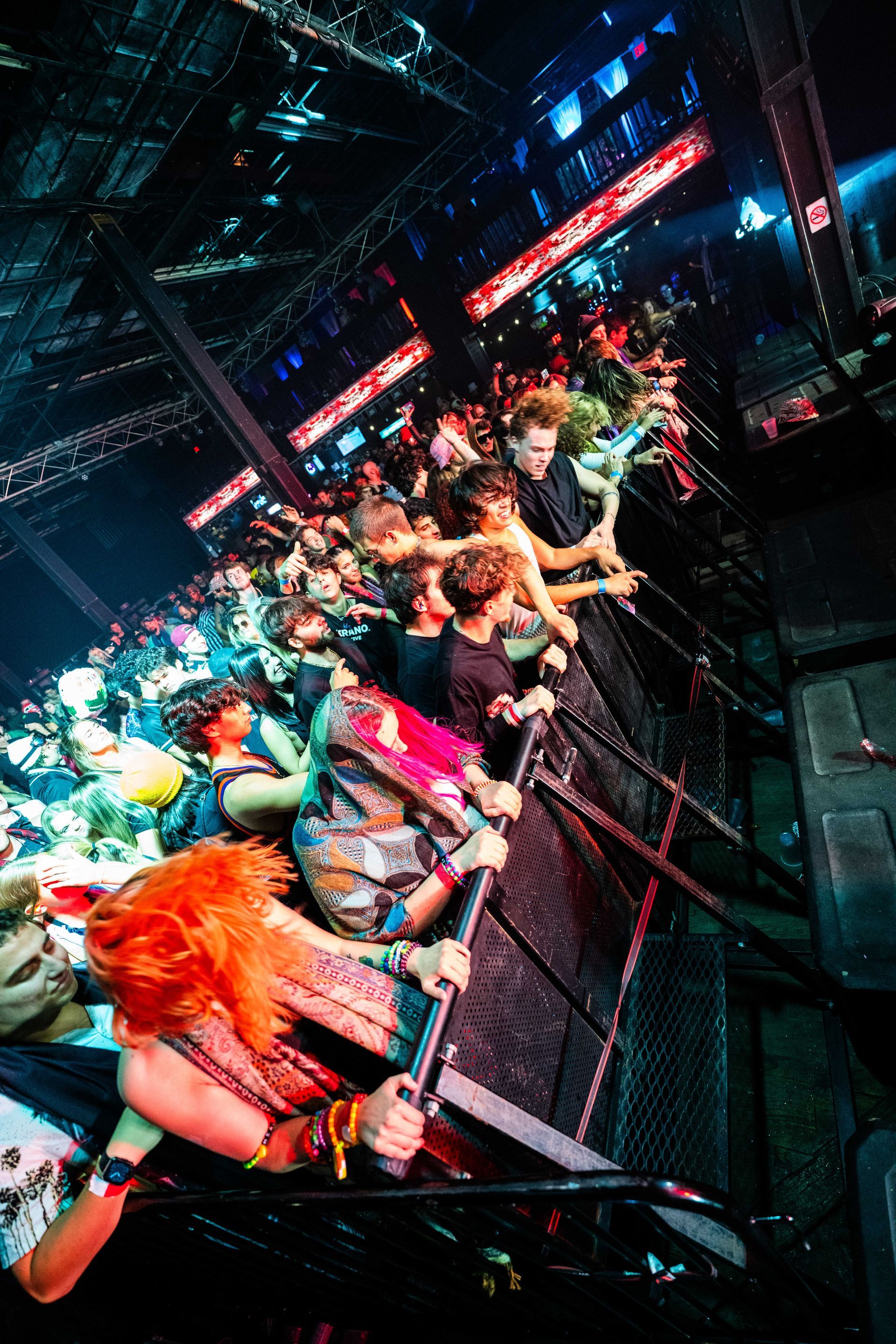 A crowd of people are standing in front of a stage at a concert.