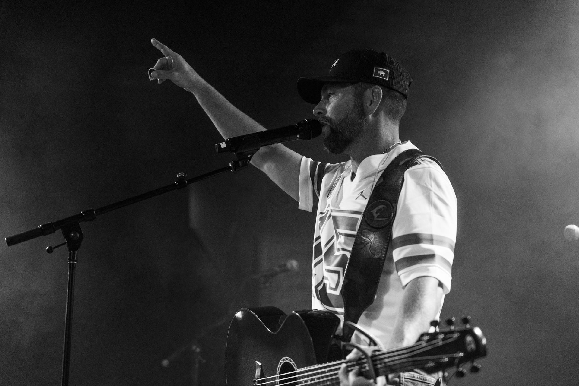 A man is singing into a microphone while holding a guitar.