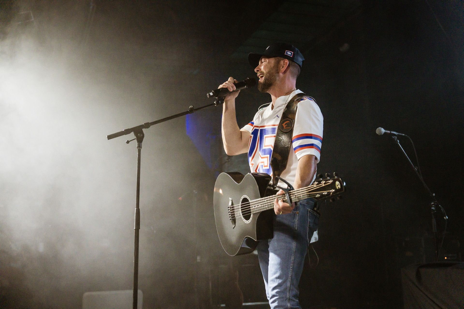 A man is playing a guitar and singing into a microphone on a stage.