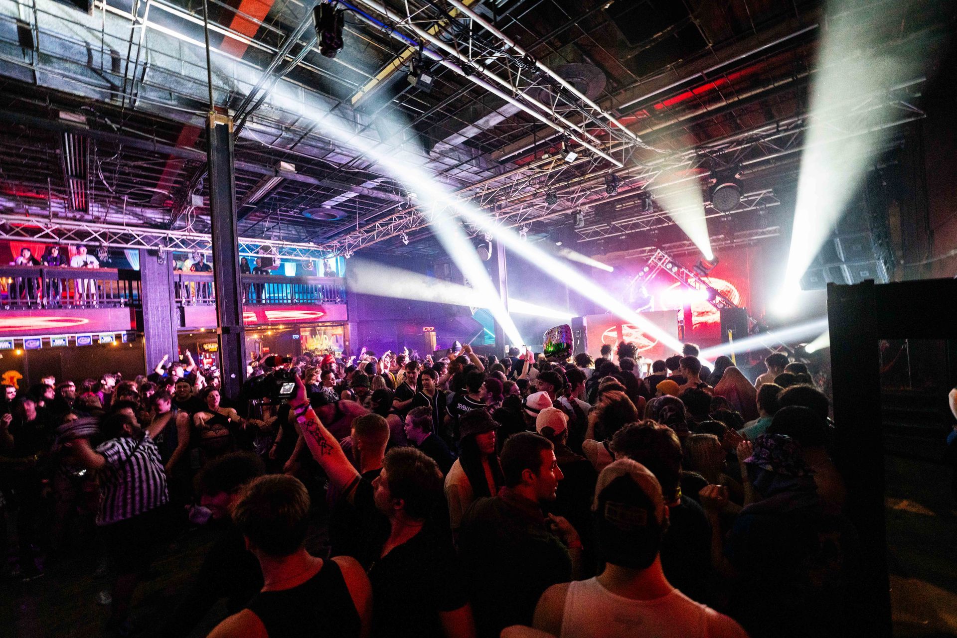 A crowd of people are standing in a dark room at a concert.