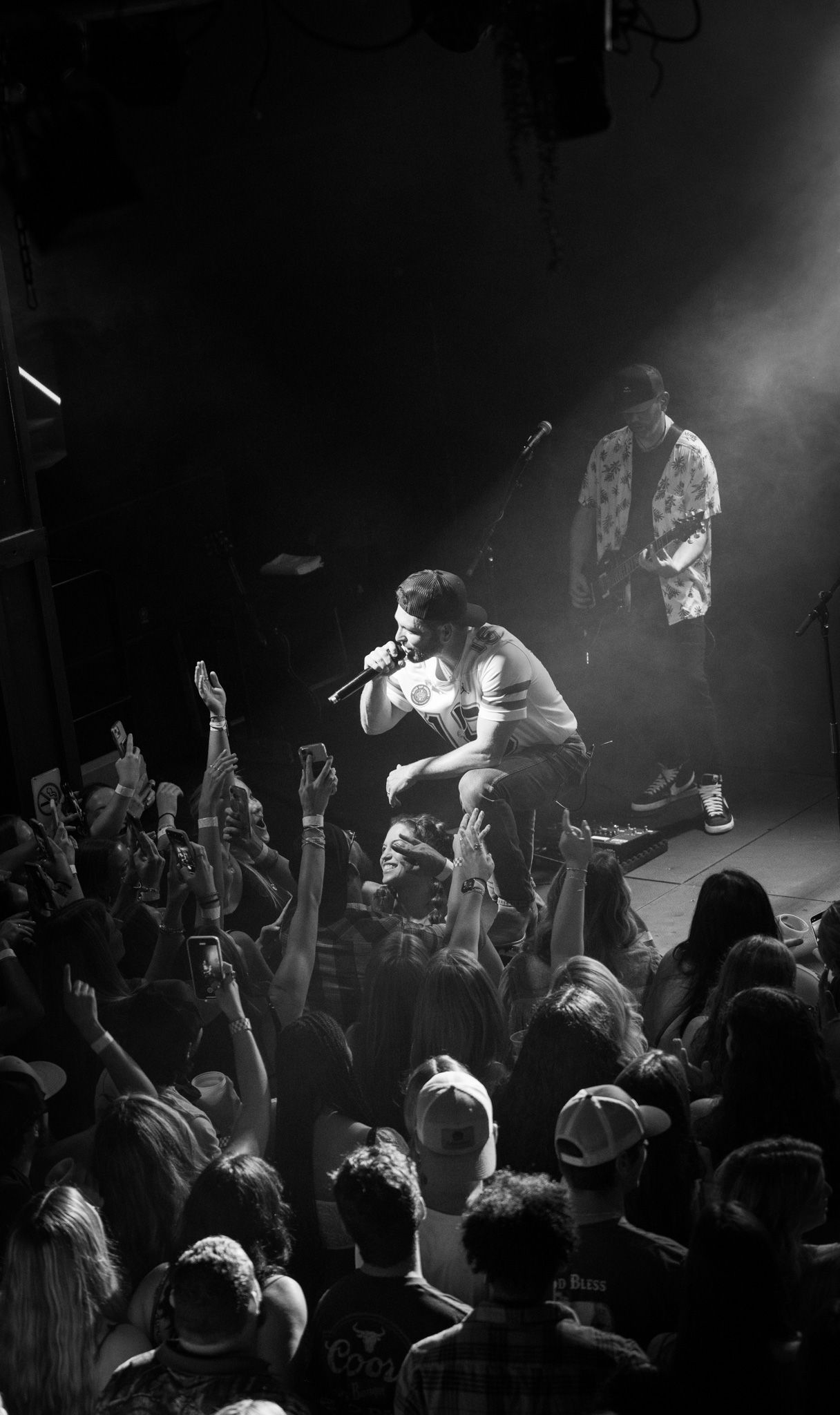 A man is singing into a microphone on a stage in front of a crowd.