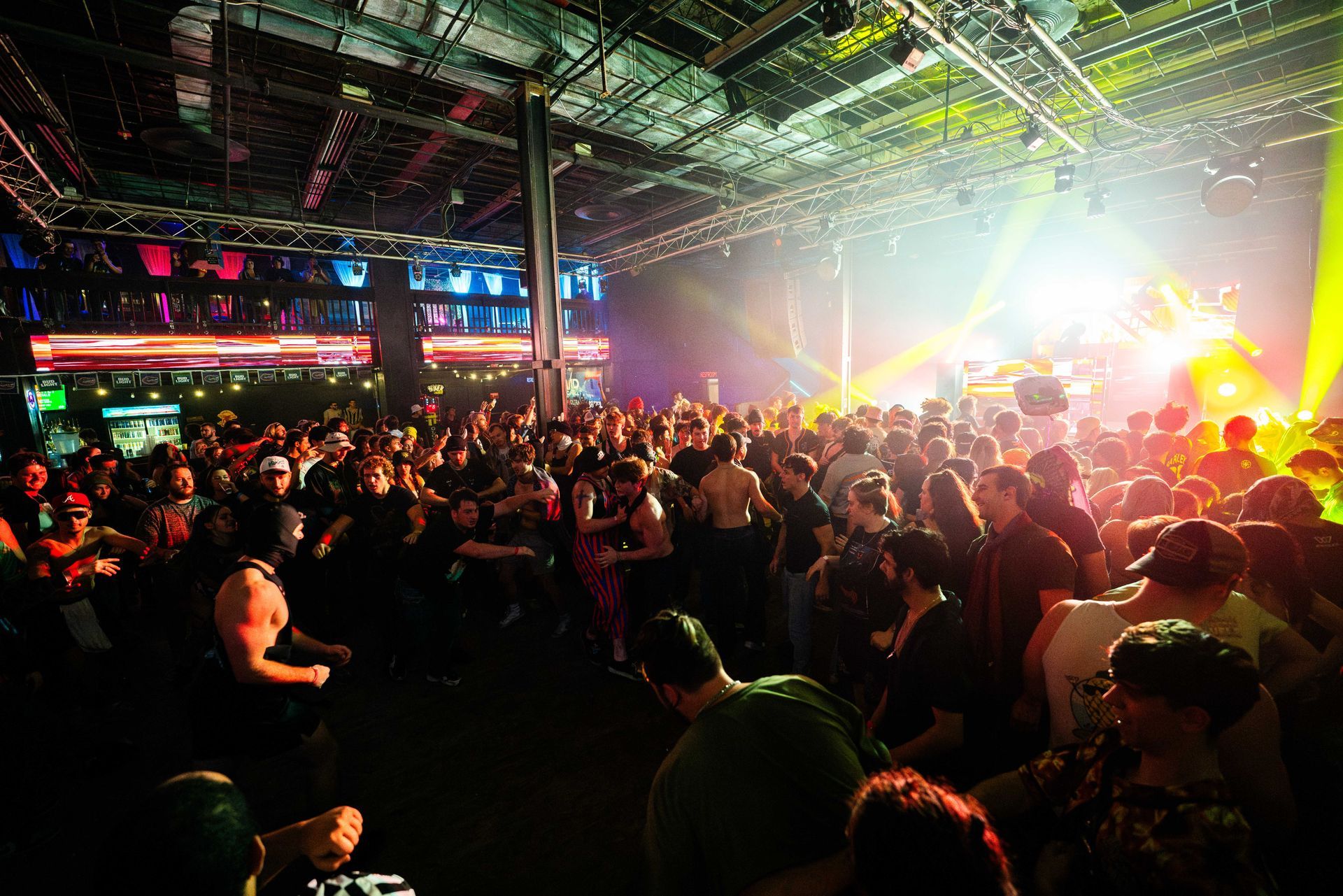 A large crowd of people are dancing in a club at a concert.
