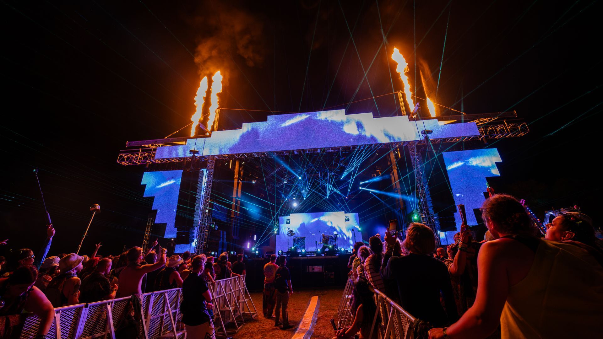 A crowd of people are standing in front of a stage at a concert.