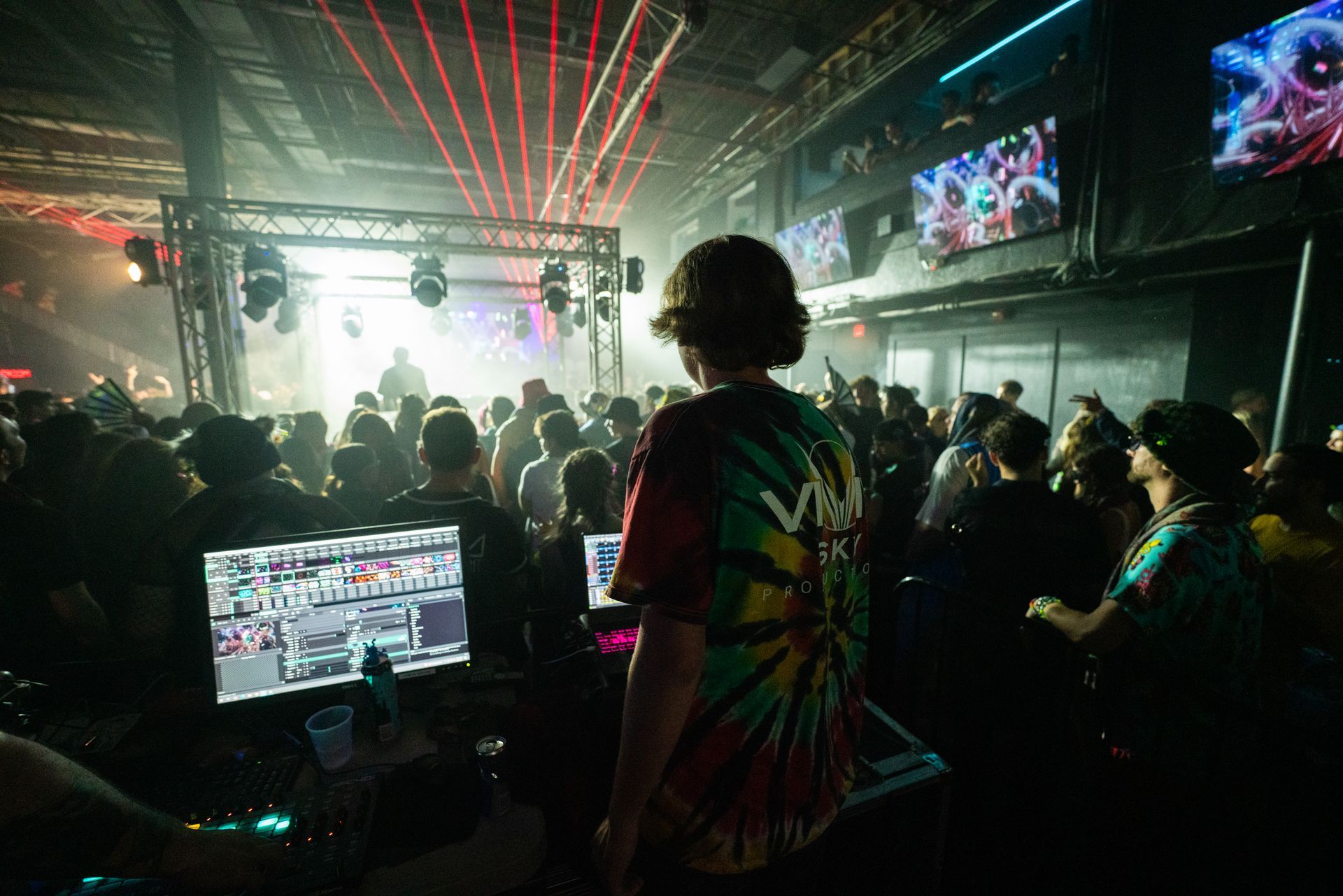 A man is standing in front of a crowd of people in a club.