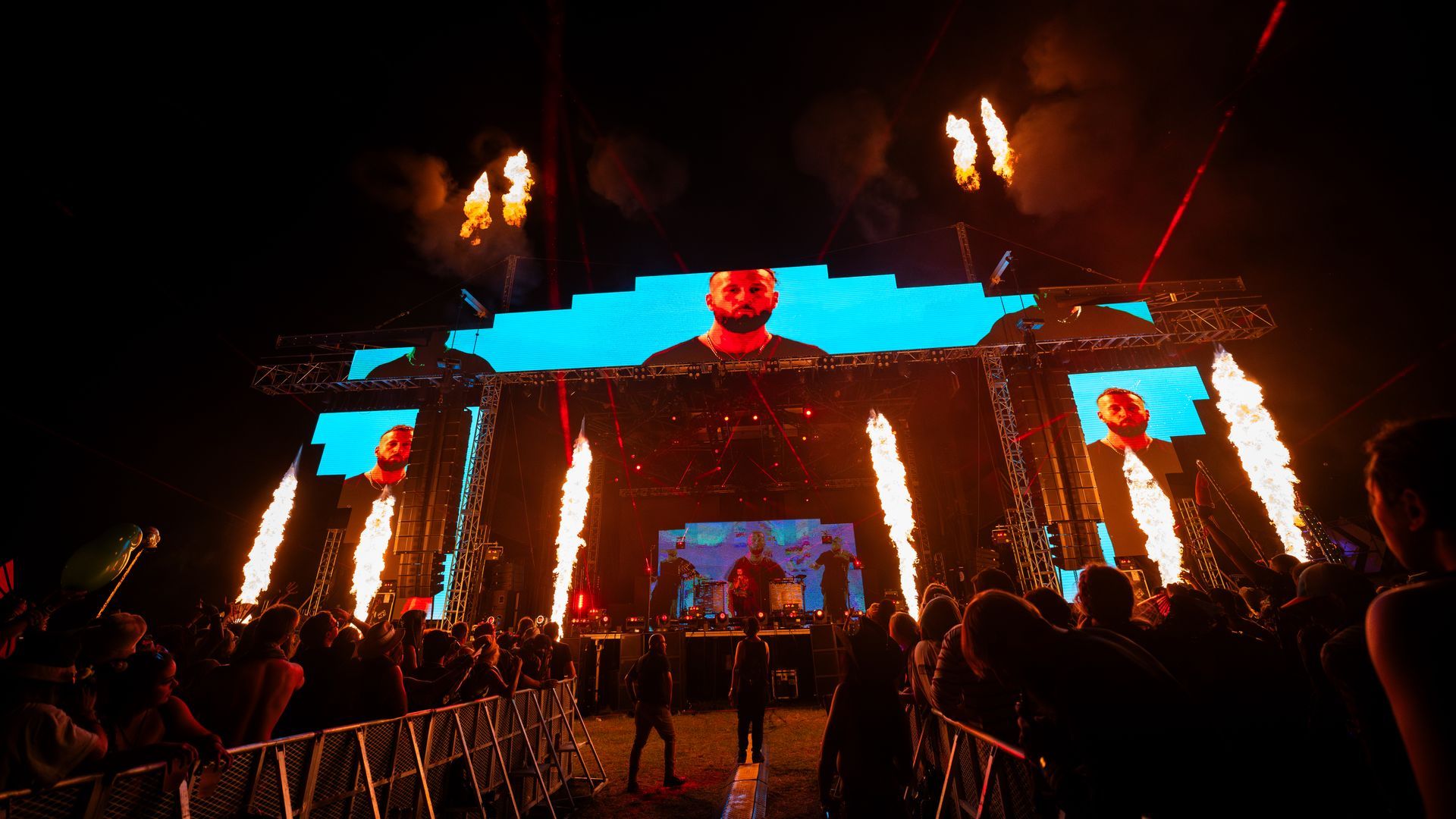 A crowd of people are standing in front of a stage at a concert.