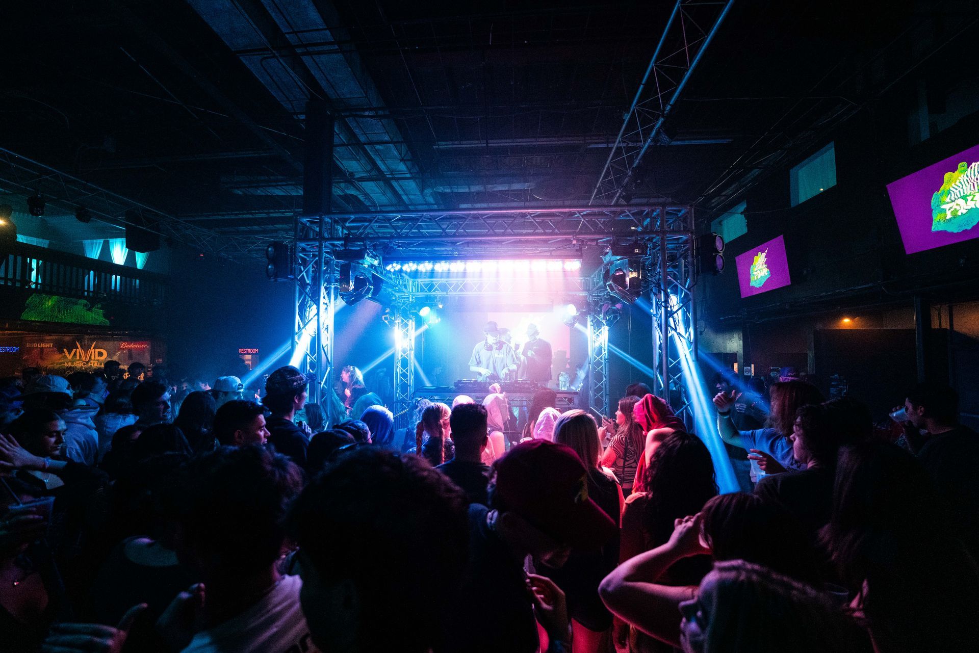 A crowd of people are dancing in a club at a concert.