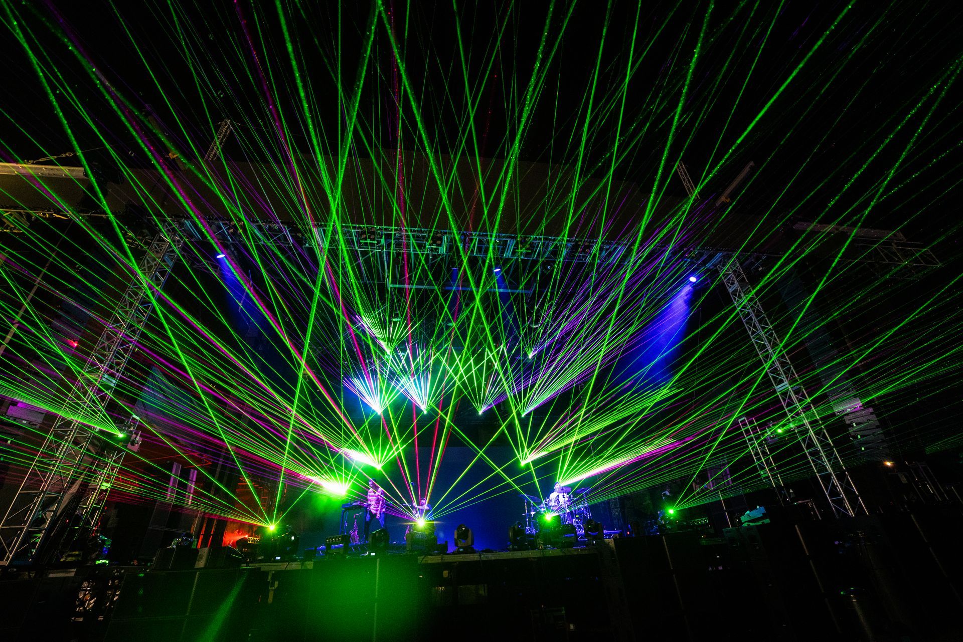 A crowd of people are watching a laser show at a concert.