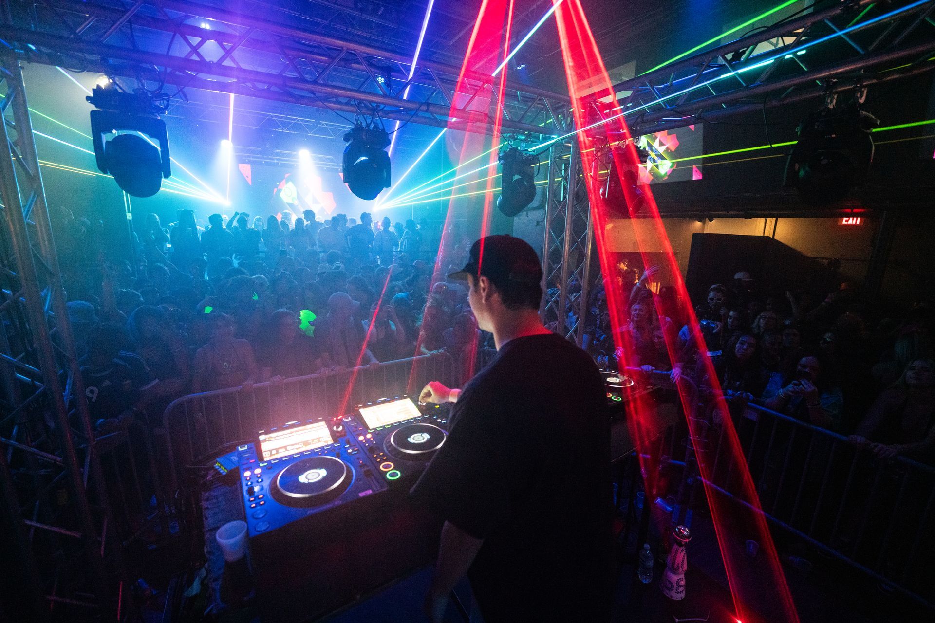 A dj is playing music in front of a crowd in a club.