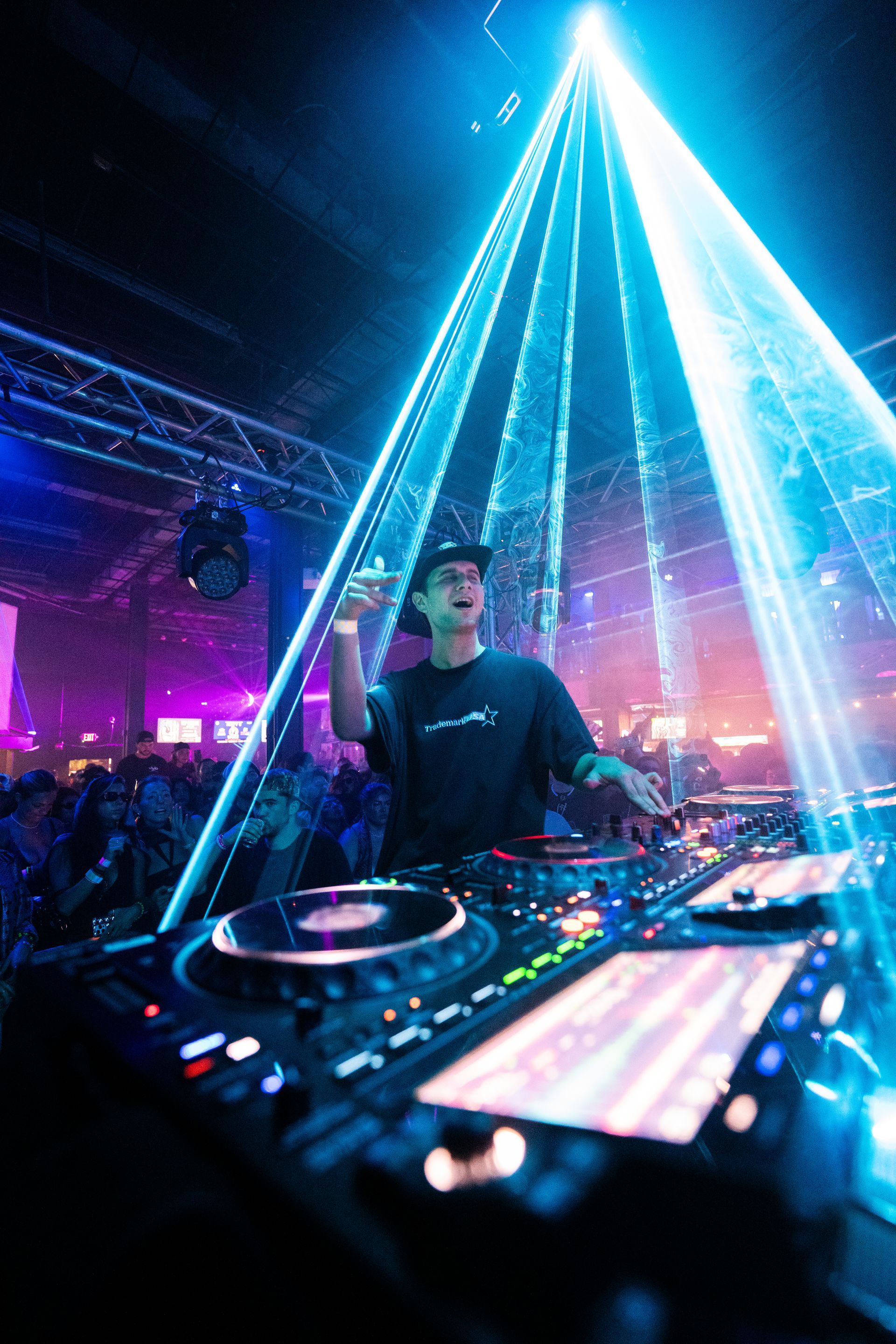A dj is playing music in front of a crowd in a club.