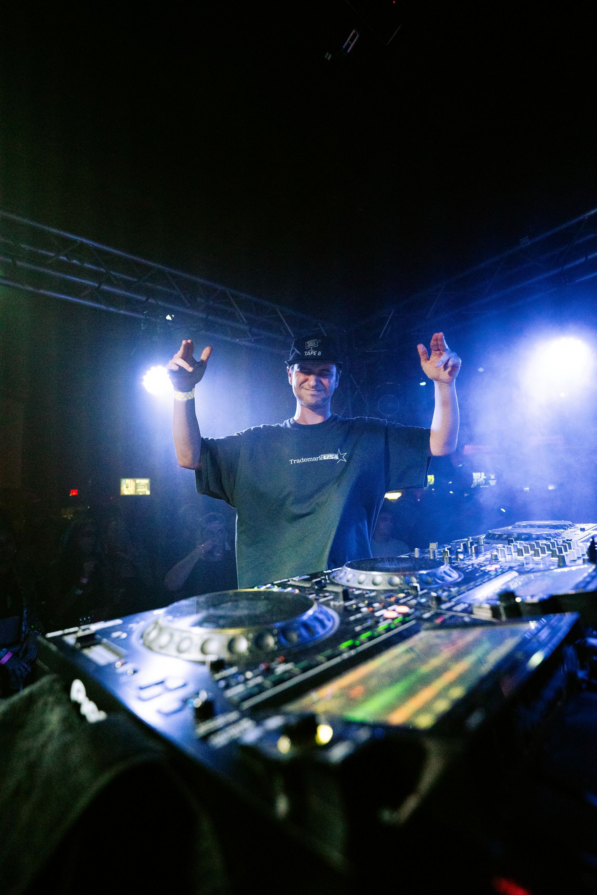 A man is standing in front of a dj mixer in a dark room.