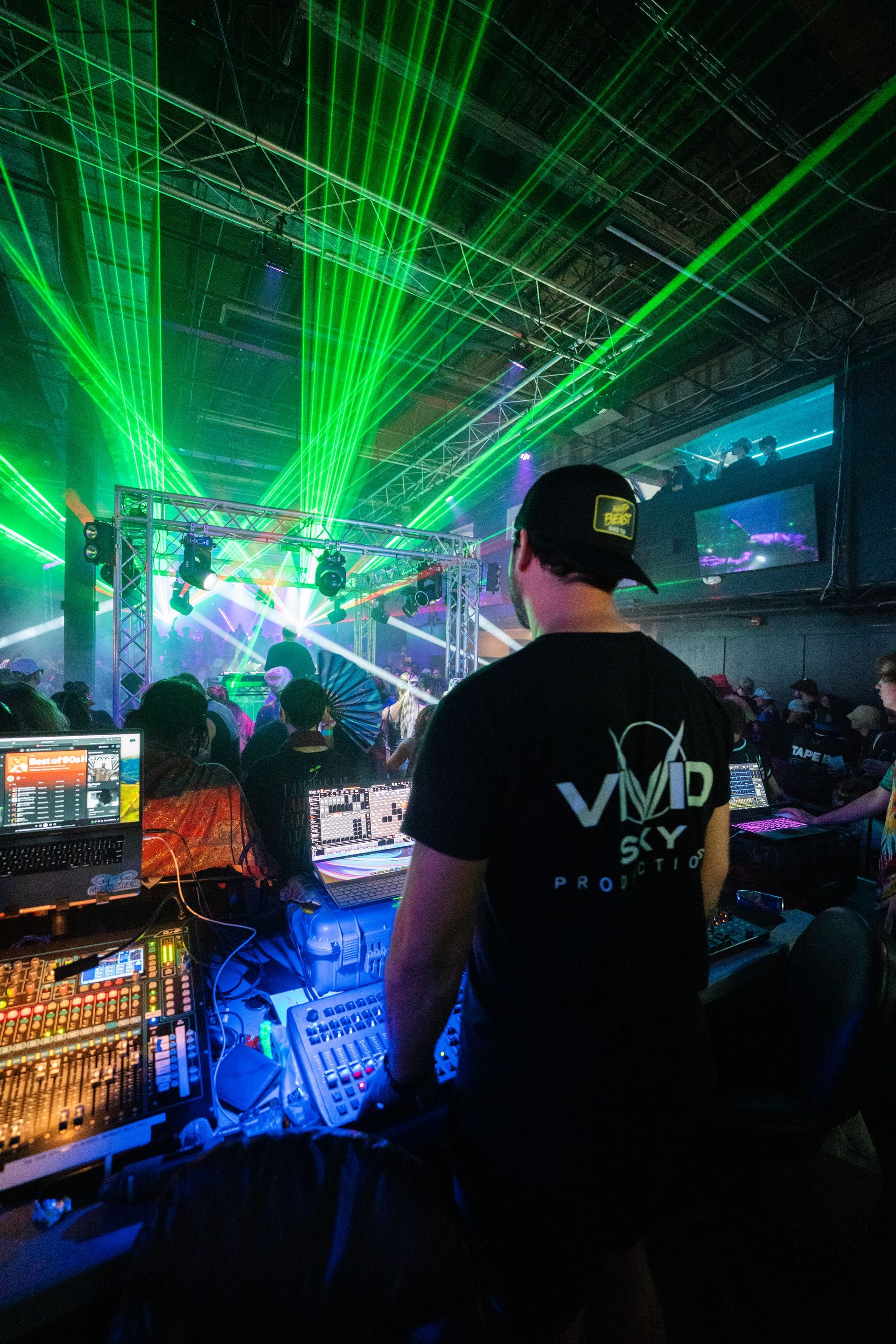 A man is standing in front of a dj booth at a party.