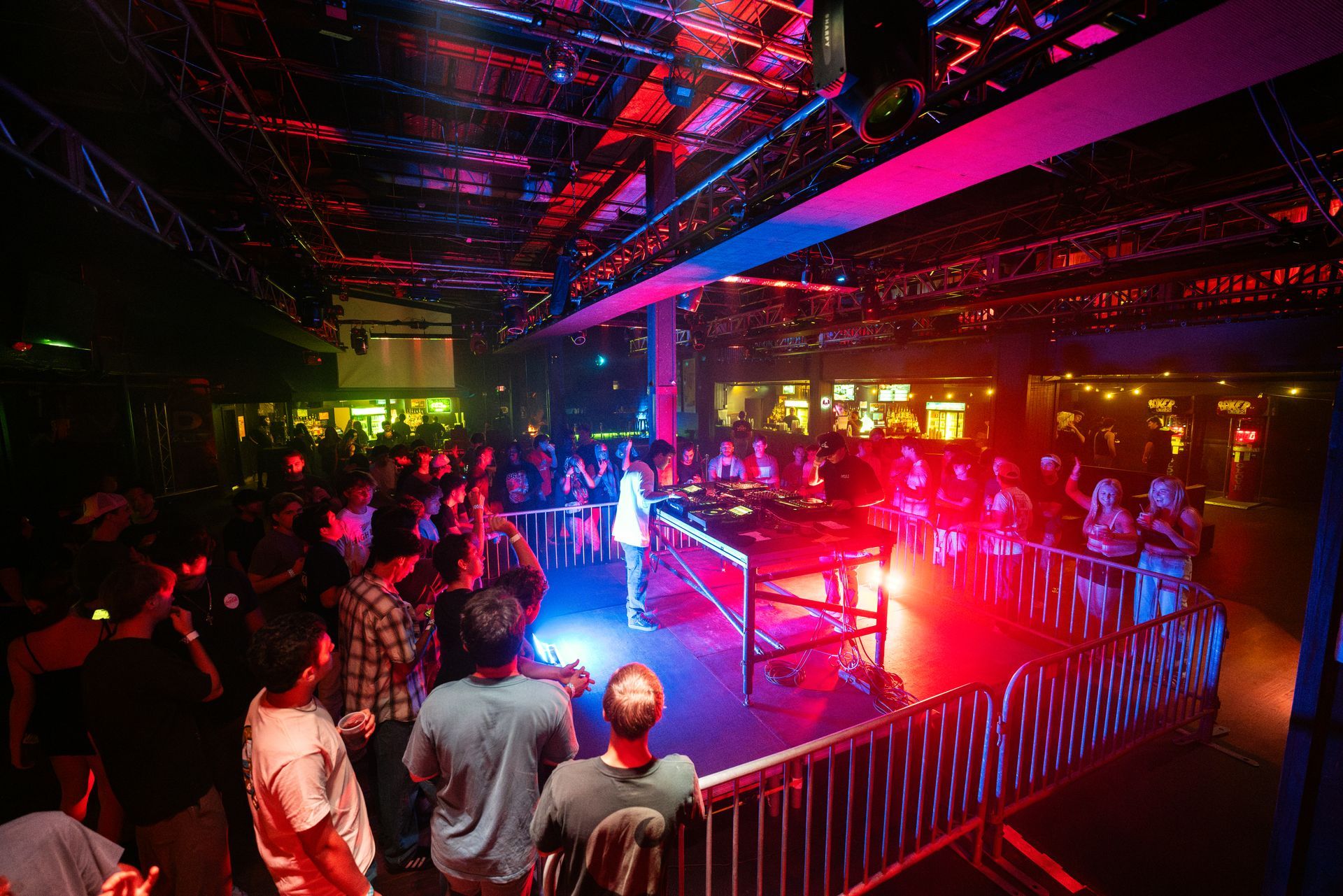 A crowd of people watching a dj on stage at a club