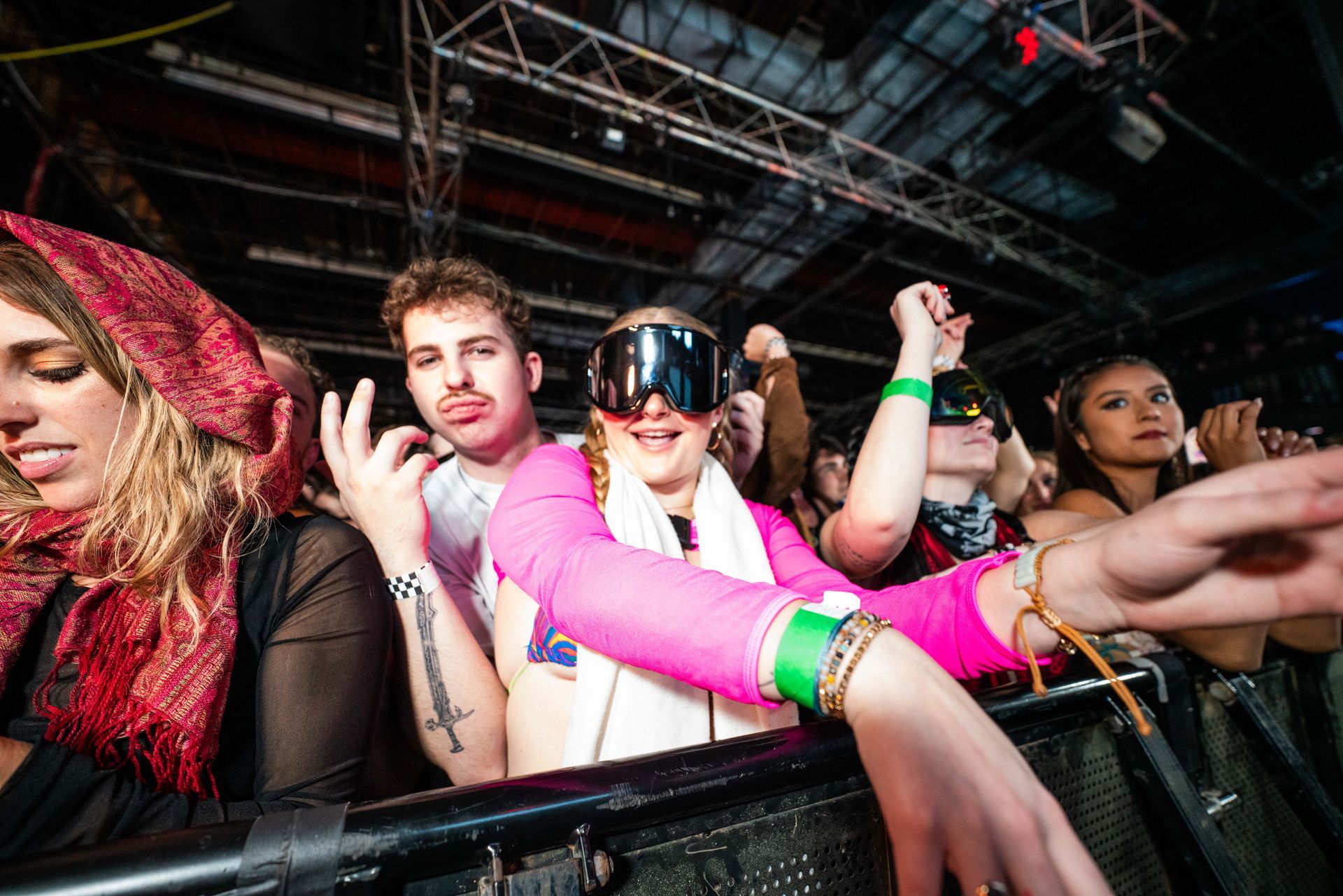 A group of people are sitting in a crowd at a concert wearing goggles.