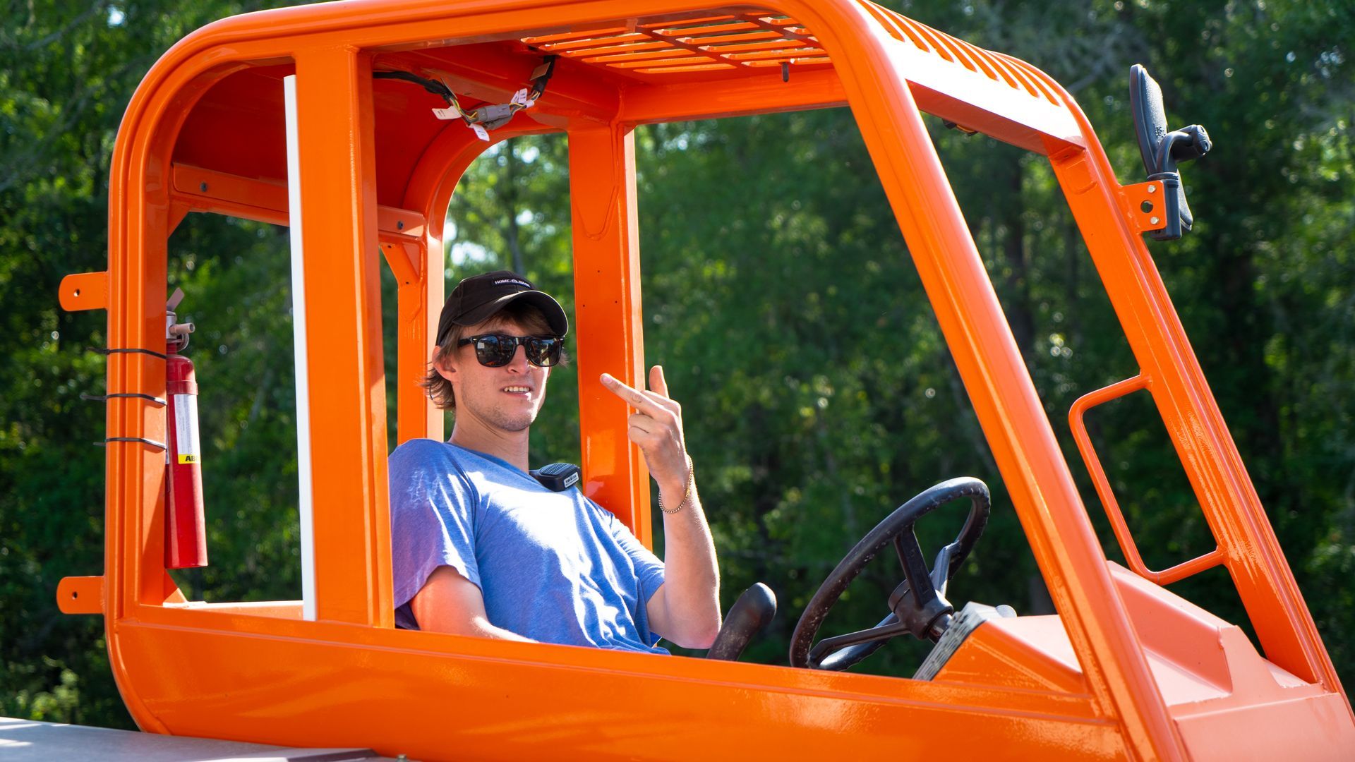 A man is sitting in the driver 's seat of an orange vehicle.