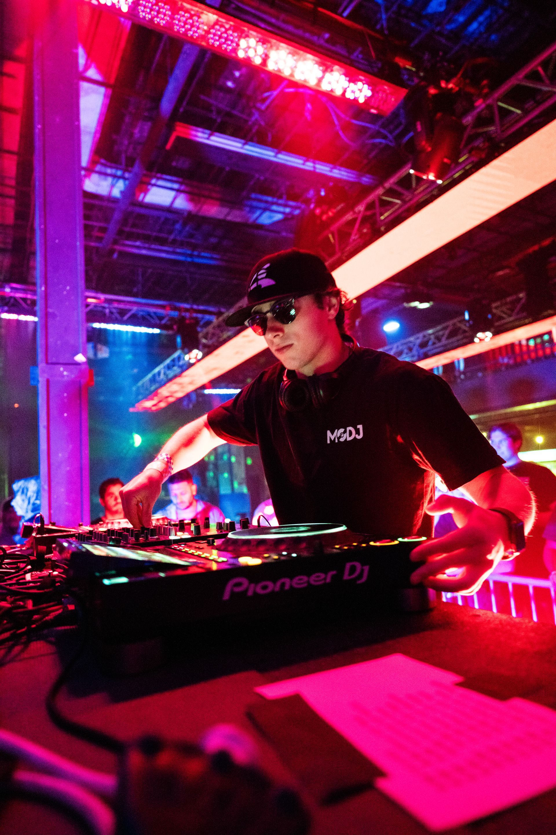 A man is playing music on a pioneer dj in a club.