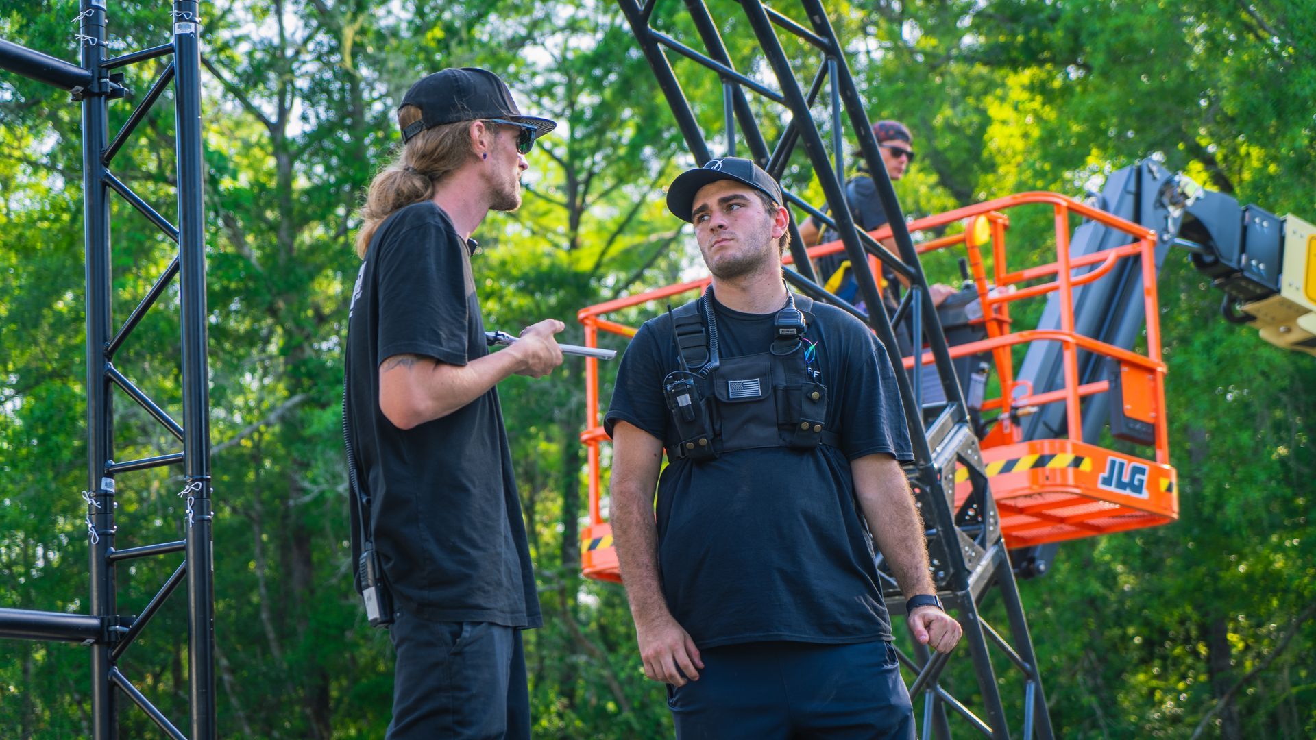 Two men are standing next to each other in front of a crane.