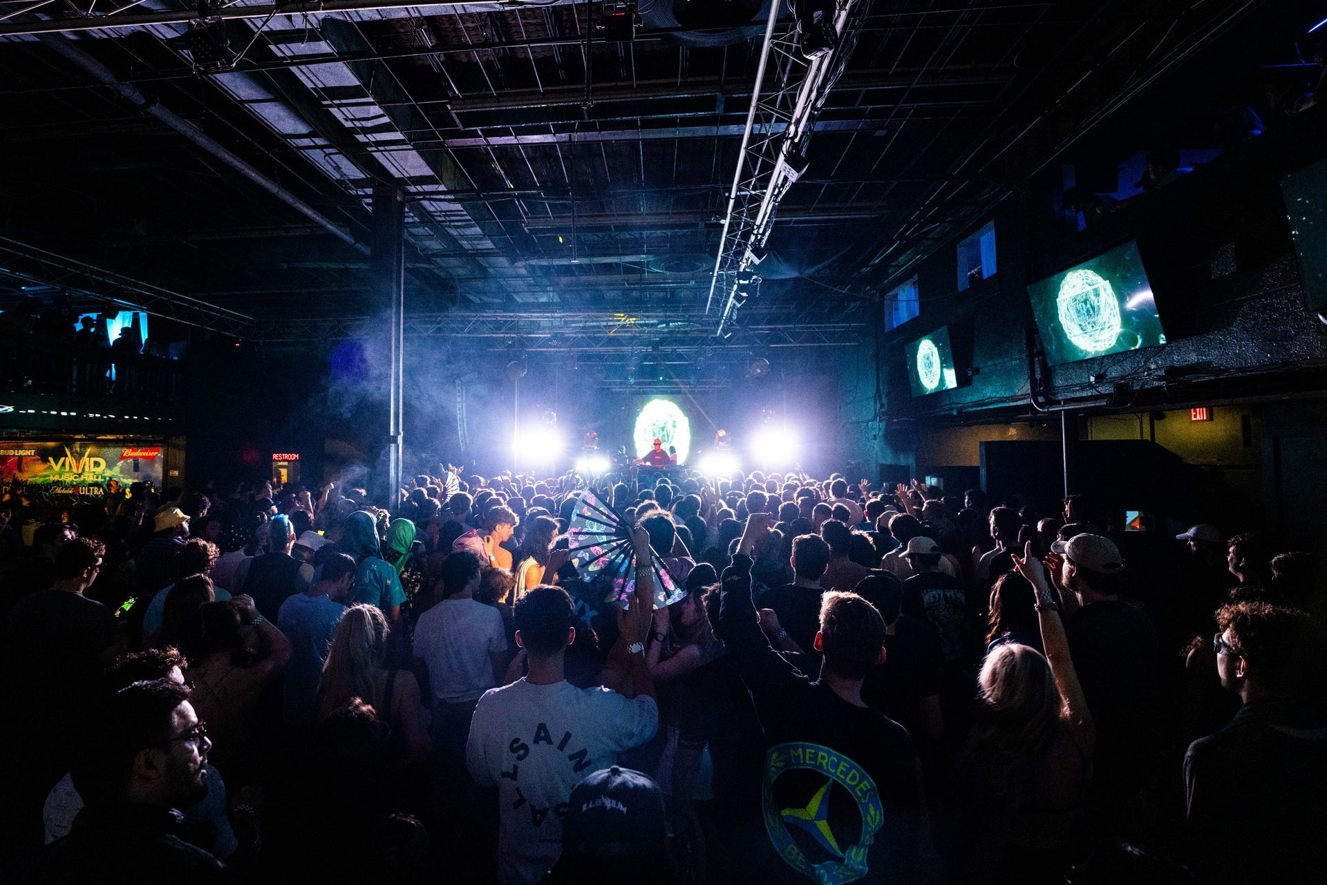 A crowd of people are standing in front of a stage at a concert.