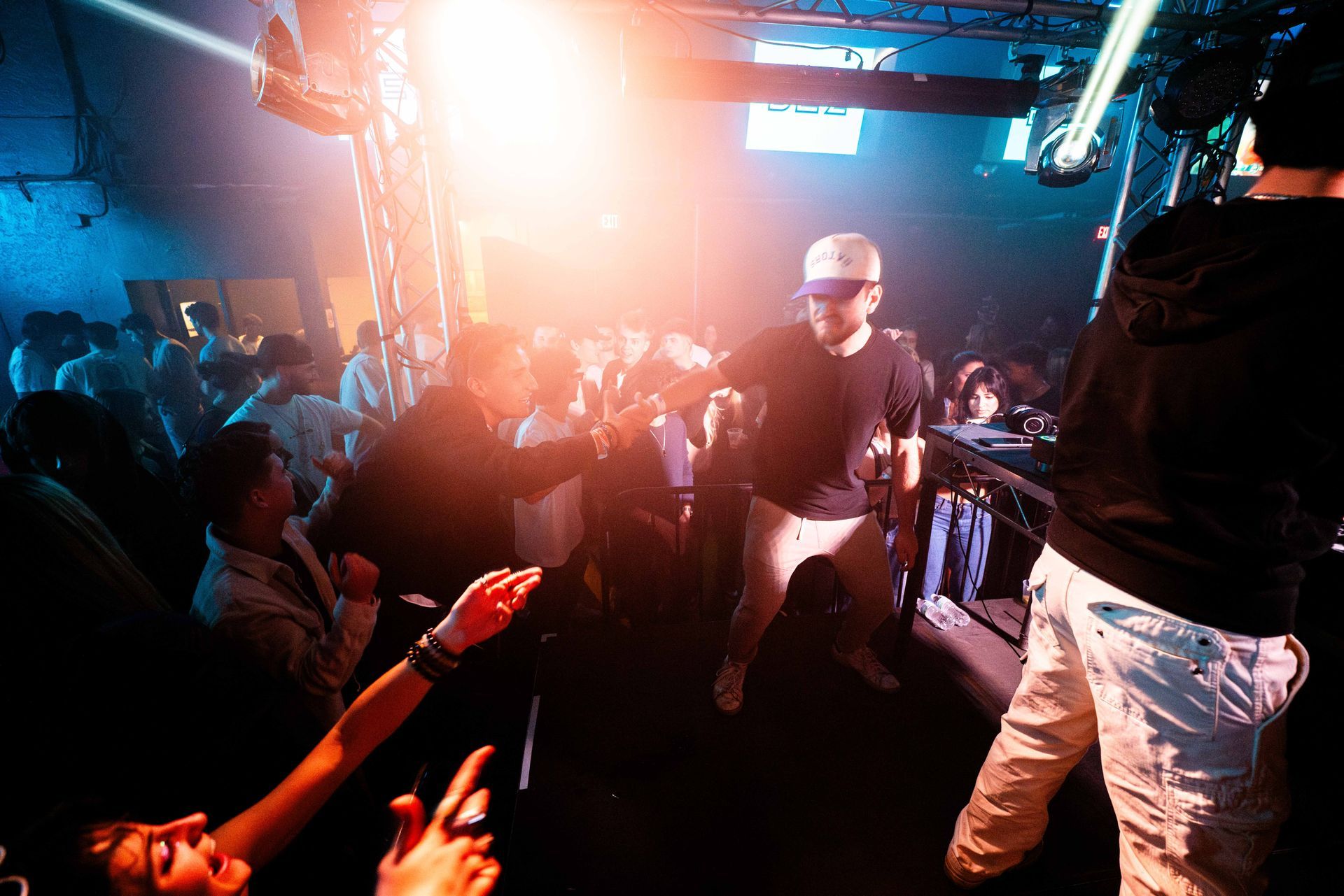 A man is standing on a stage in front of a crowd of people at a party.