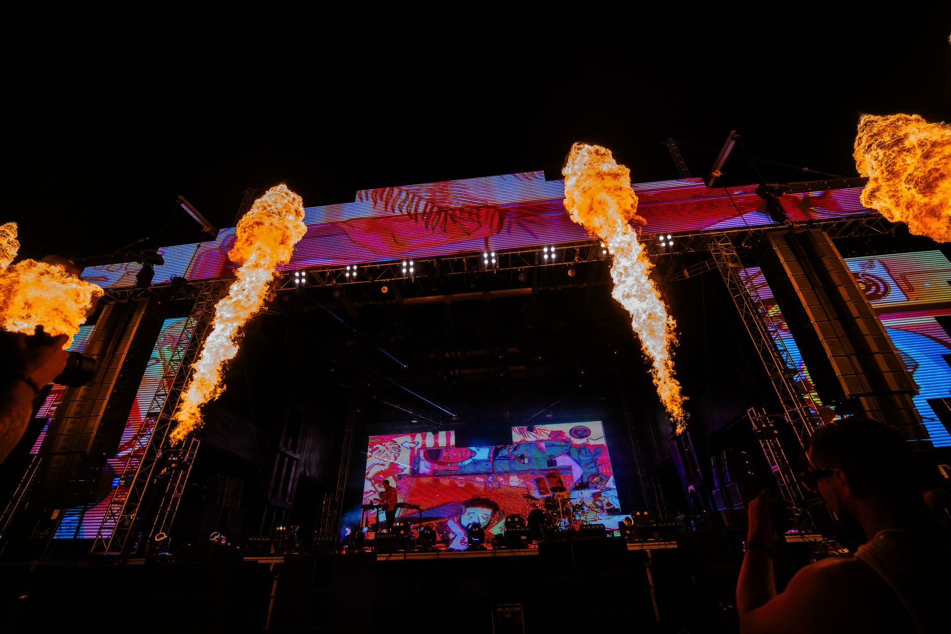 A group of people are standing in front of a stage with flames coming out of it.