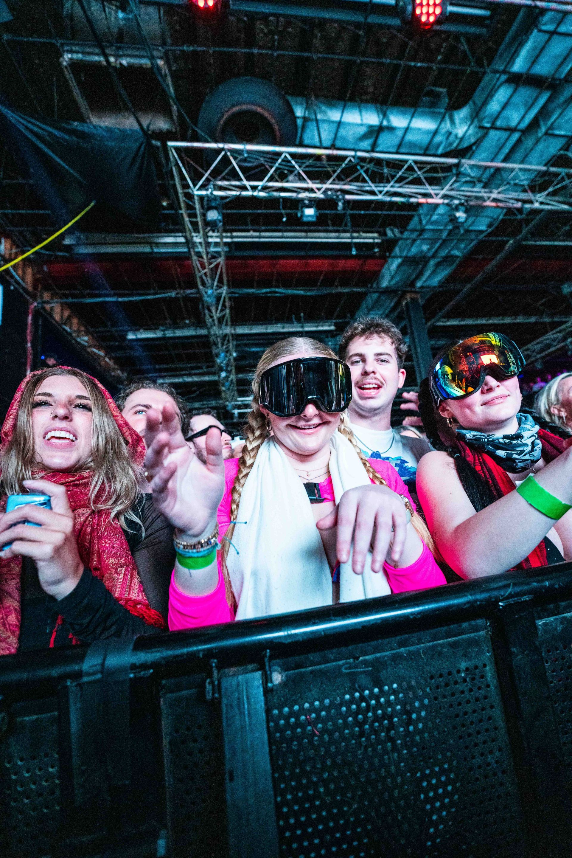 A group of people are standing in front of a fence at a concert.