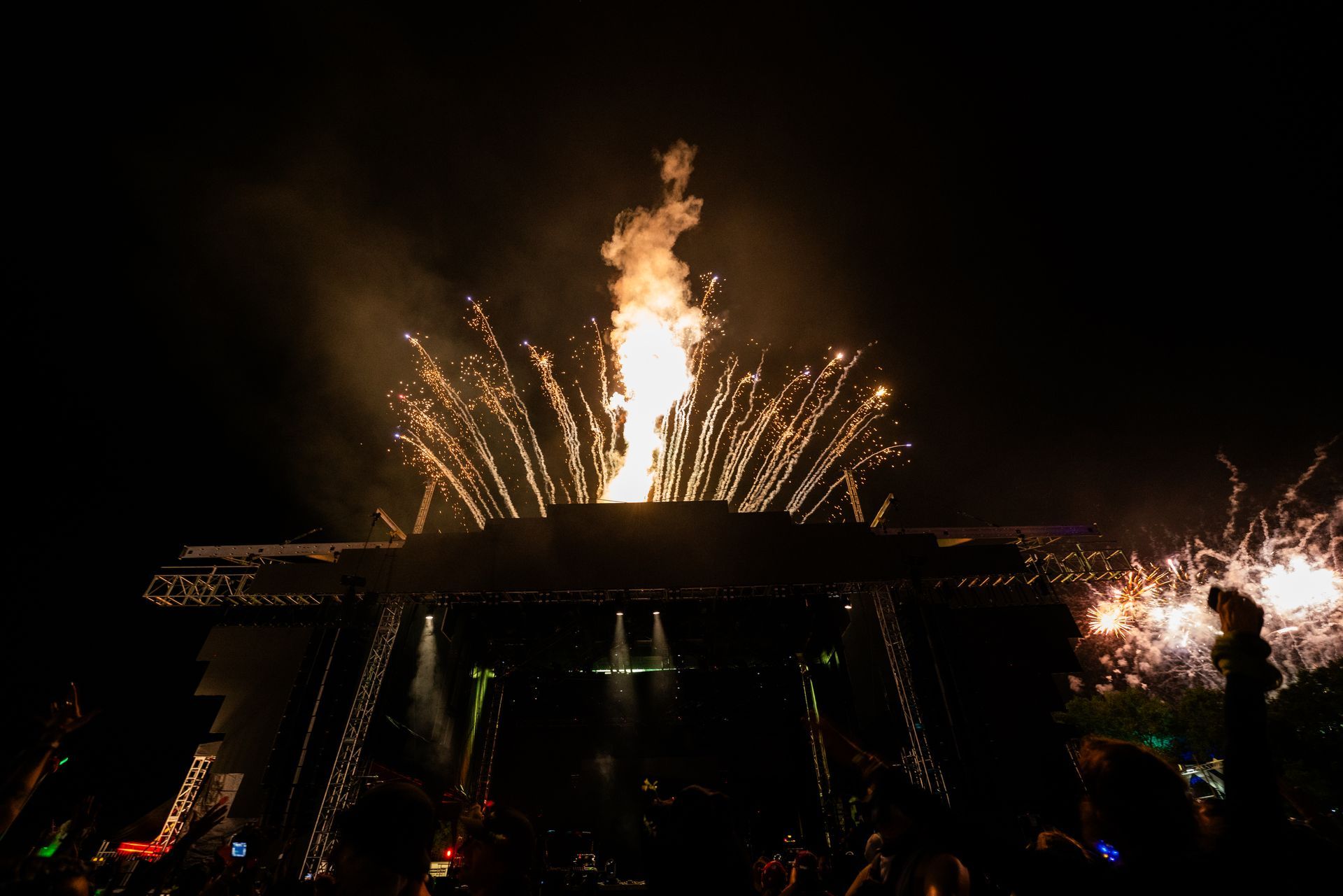 A crowd of people are watching a fireworks display at a concert.