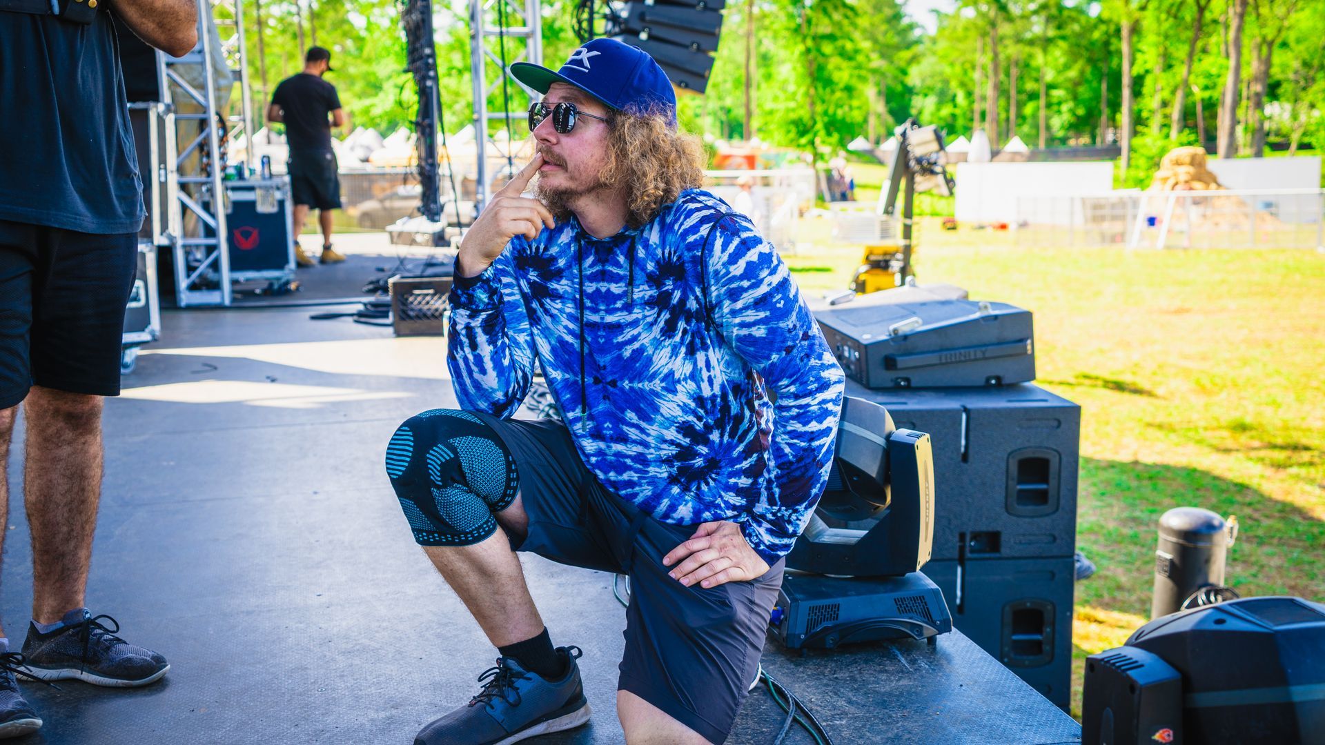 A man in a blue shirt and hat is sitting on a bench.