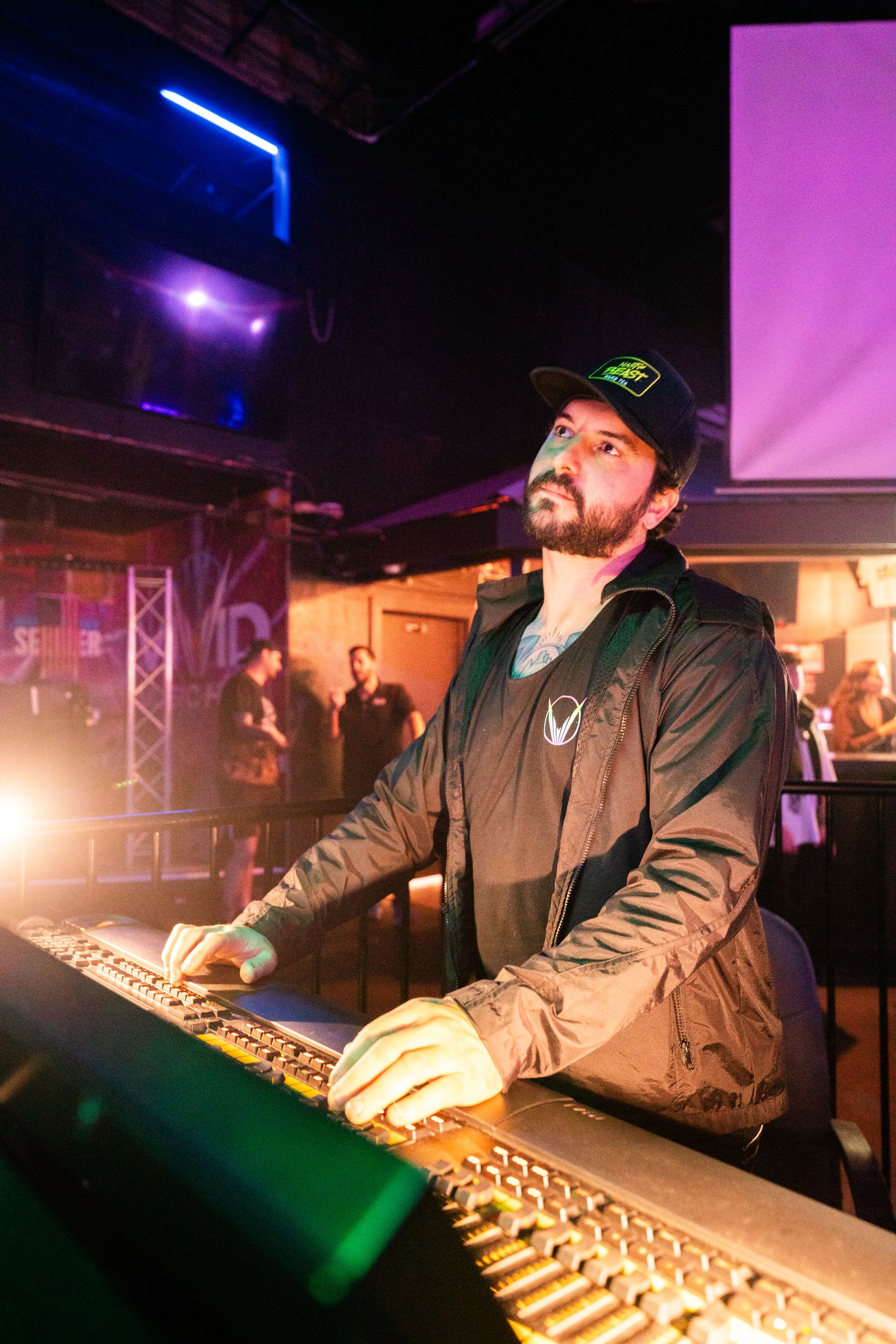 A man with a beard is playing a keyboard in a dark room.