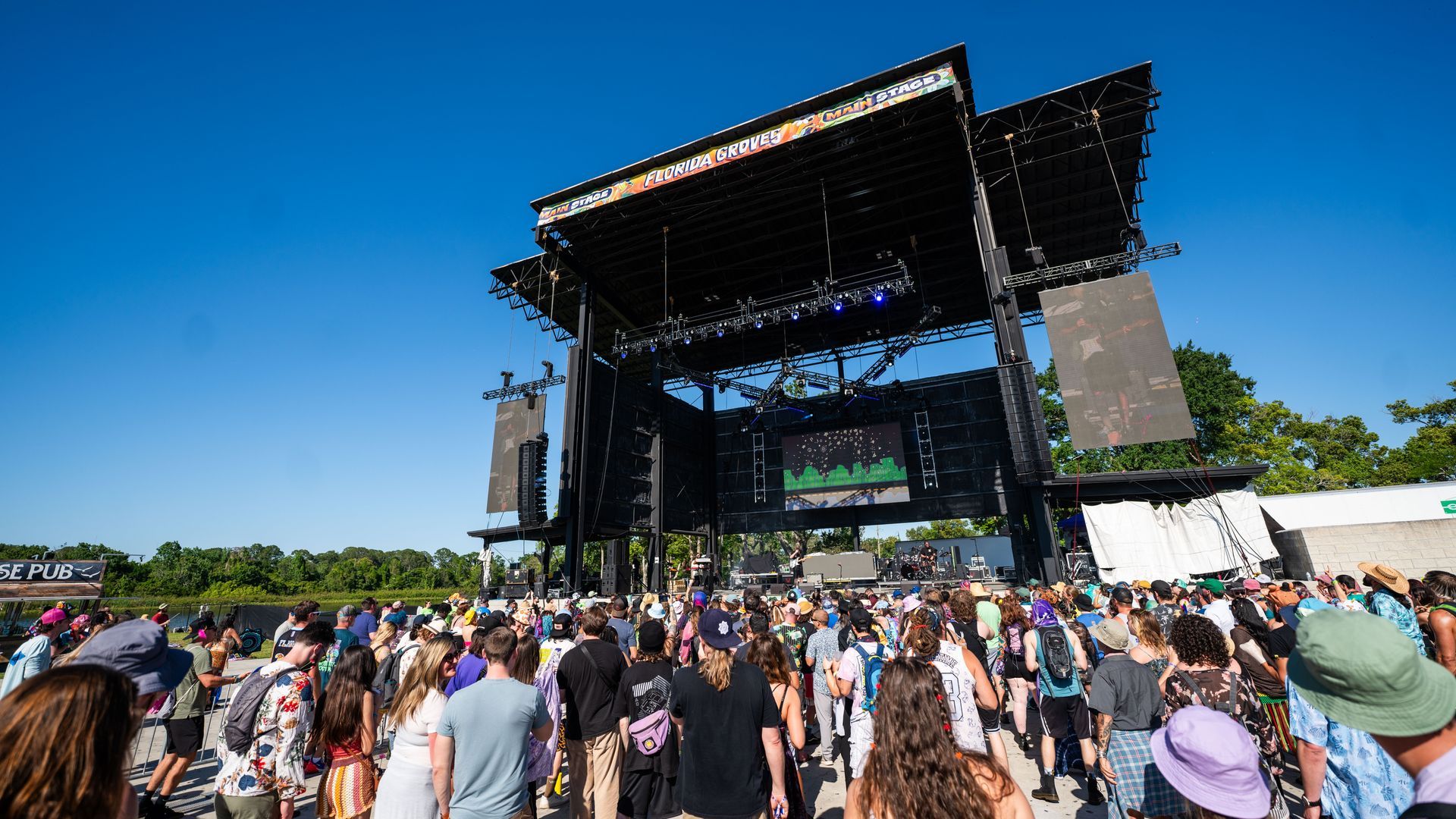 A crowd of people are standing in front of a stage at a music festival.