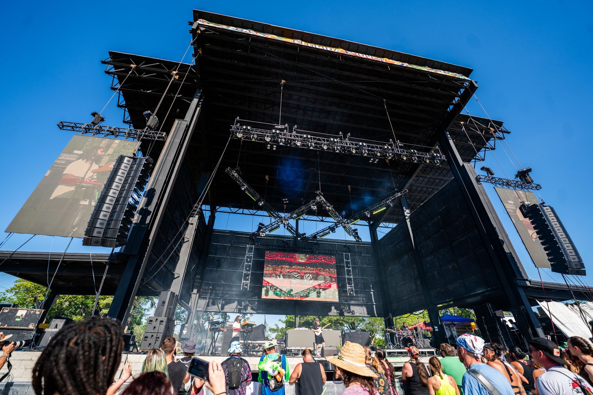 A crowd of people are gathered in front of a large stage at a concert.