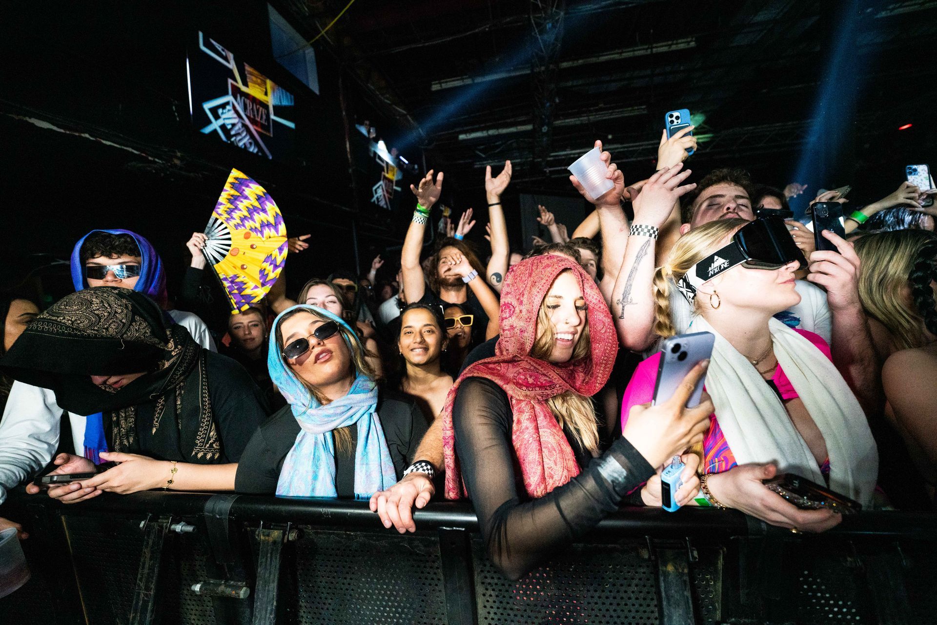 A crowd of people are standing in a dark room at a concert.