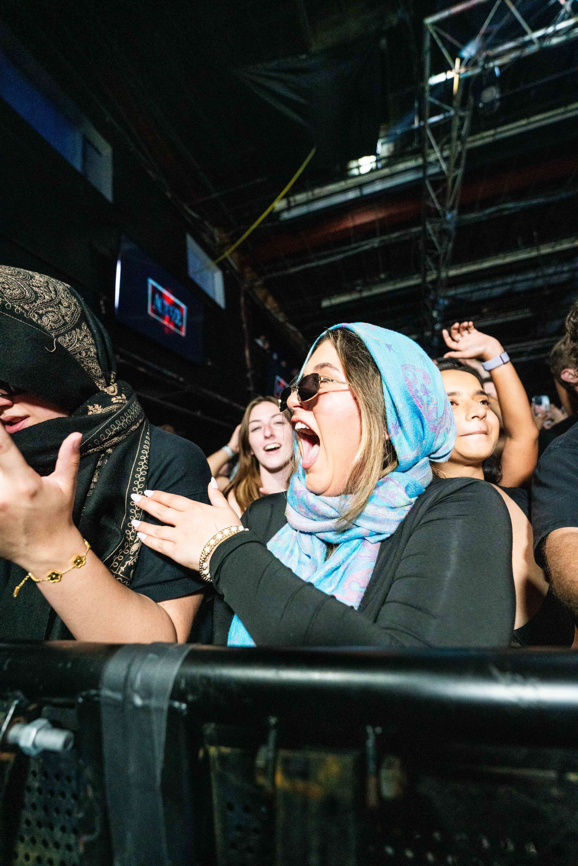 A group of people are standing in a crowd at a concert.
