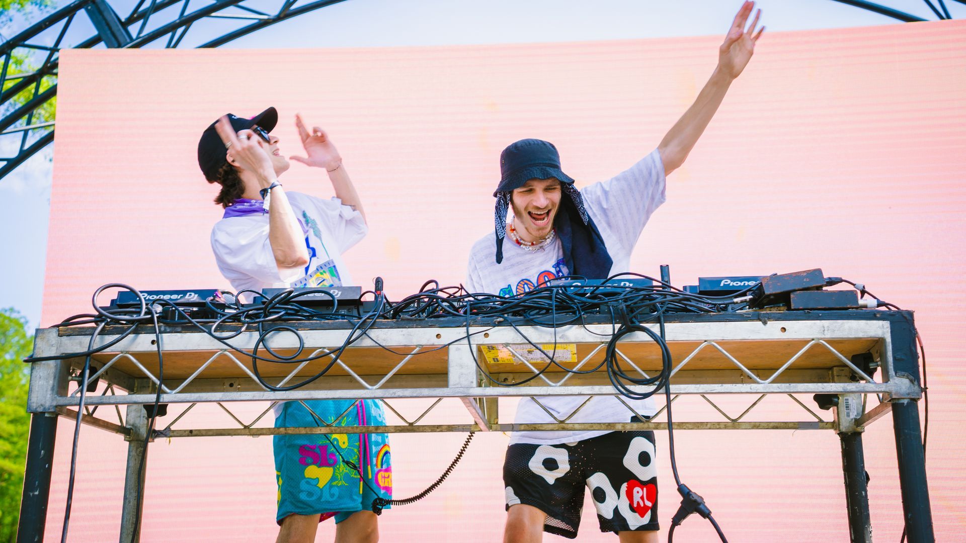 Two men are standing at a table with their arms in the air.