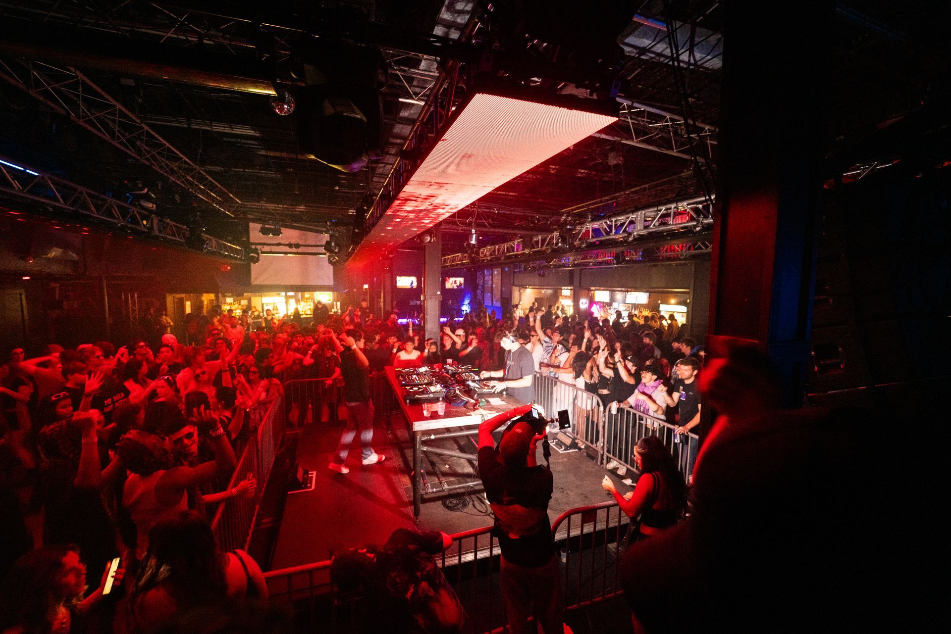 A crowd of people are gathered in a dark room at a concert.