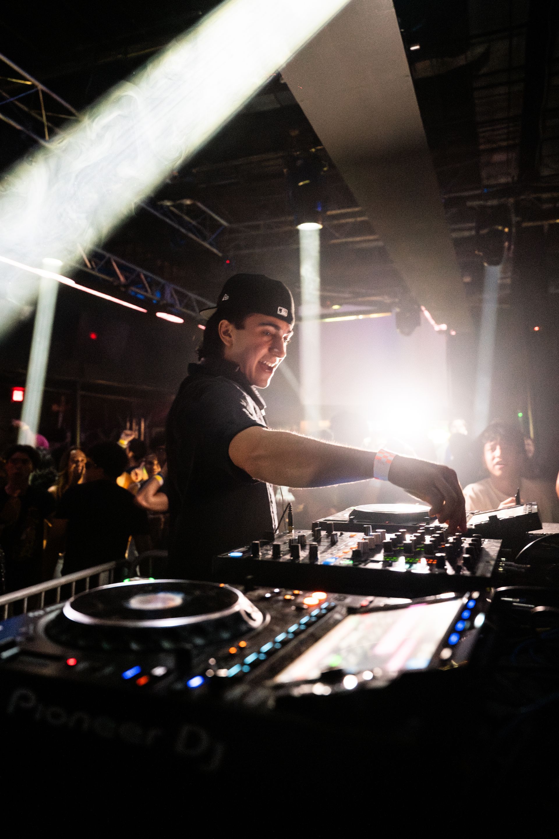 A man is playing a dj set in a dark room.