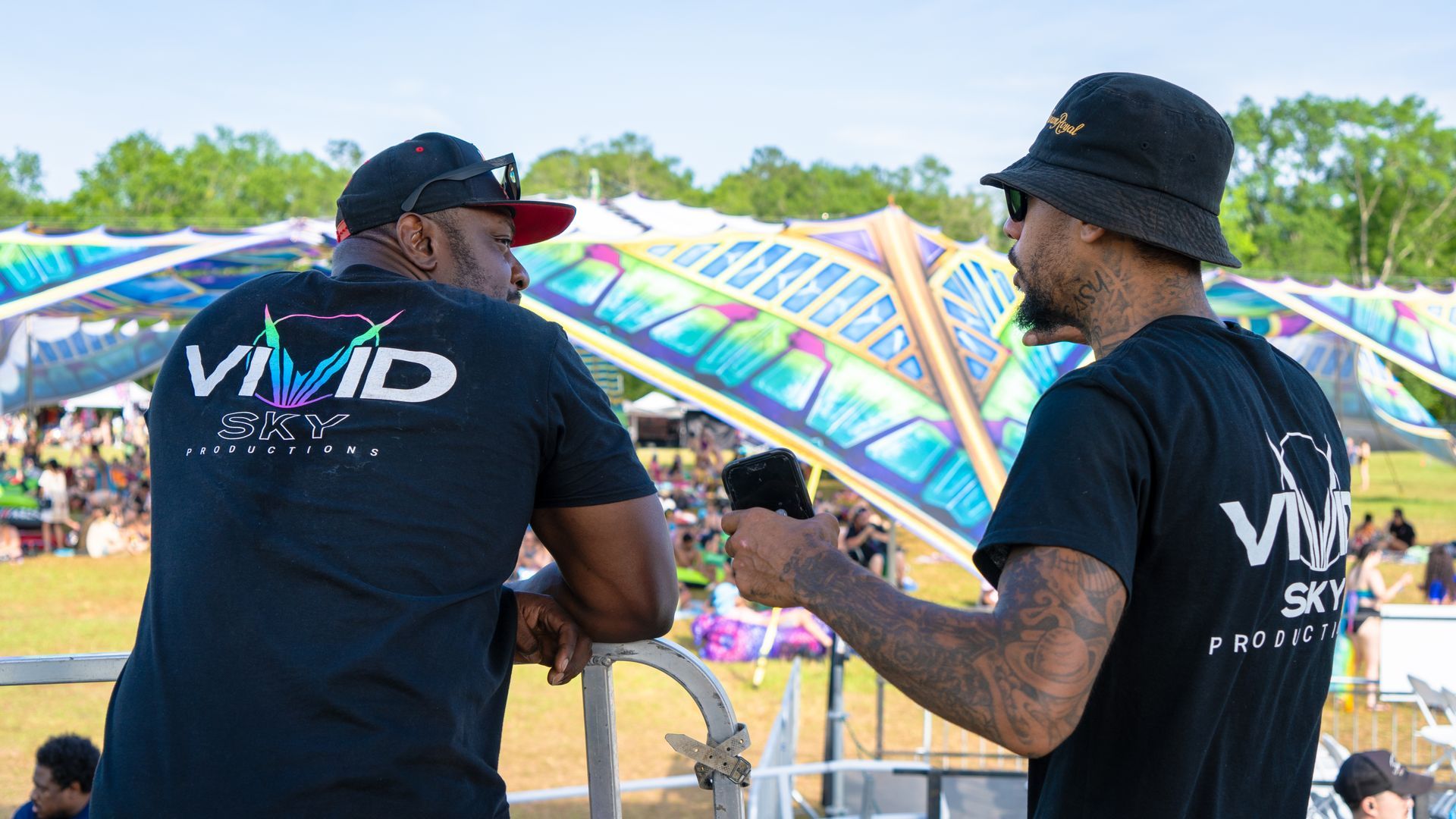 Two men are standing next to each other at a festival.