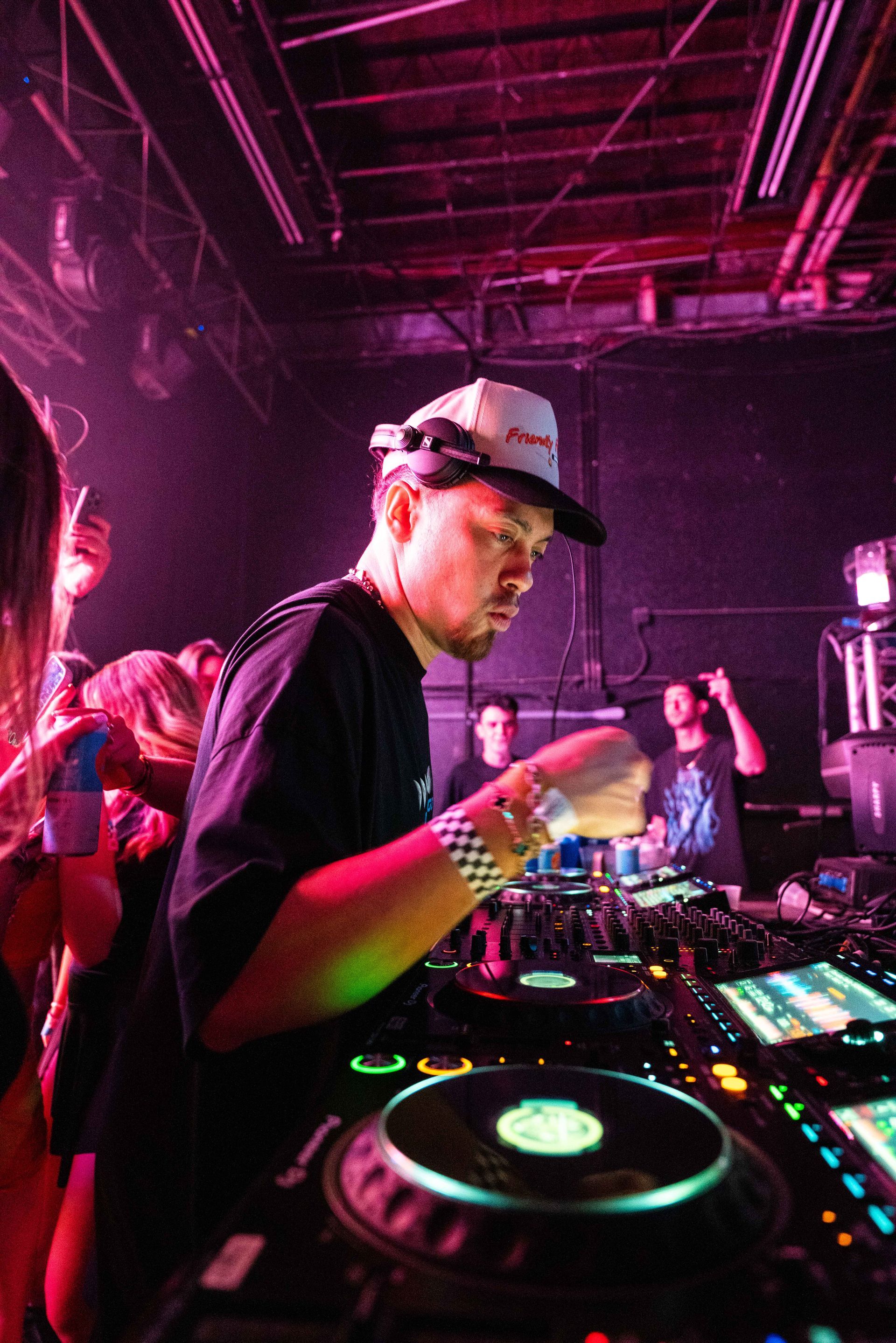 A man is playing a dj set in a dark room.