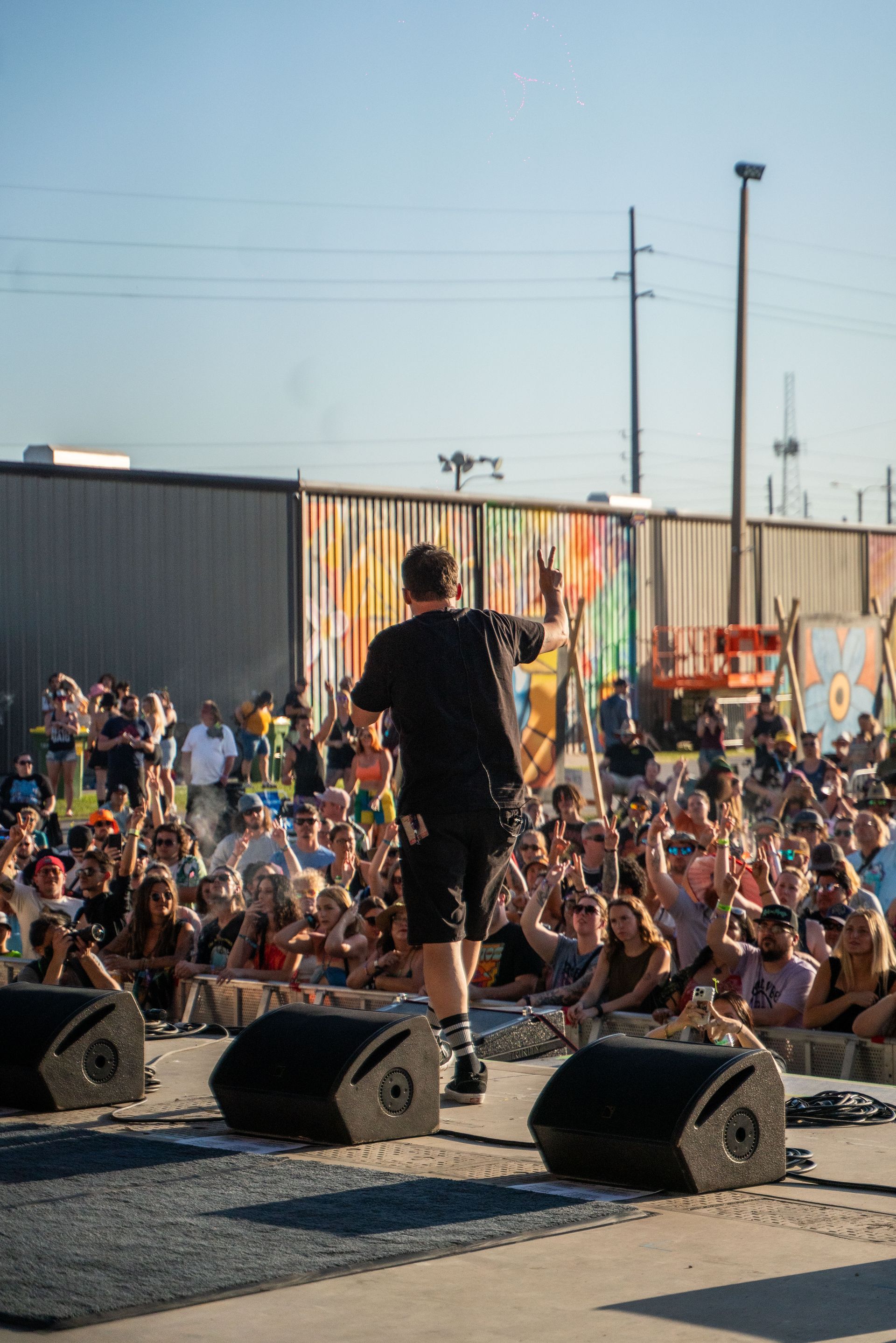 A man is standing on a stage playing a guitar in front of a crowd of people.