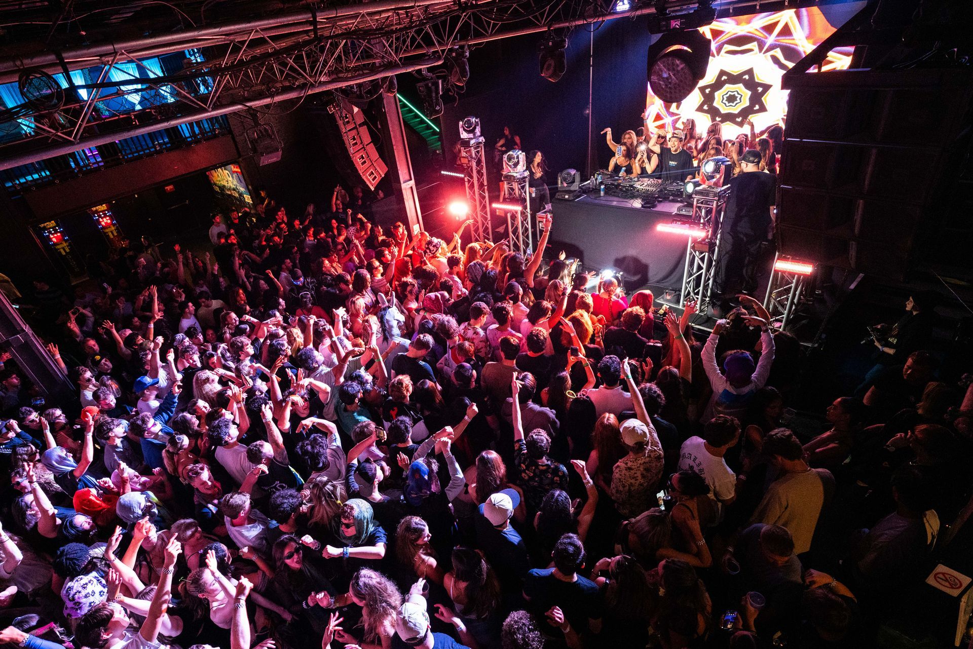 A crowd of people at a concert with their hands in the air