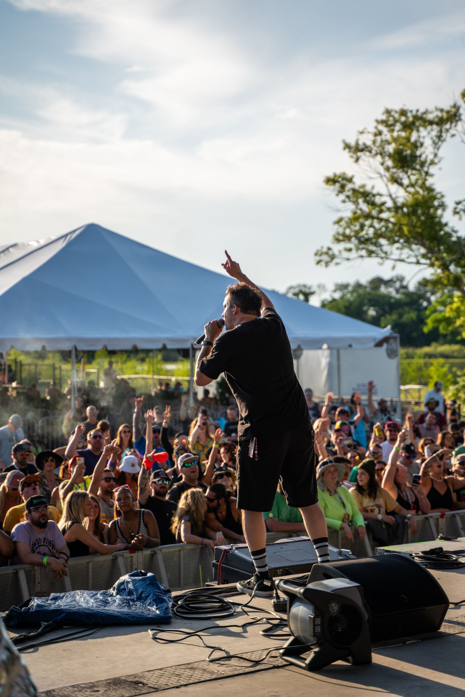A man is standing on a stage holding a microphone in front of a crowd.