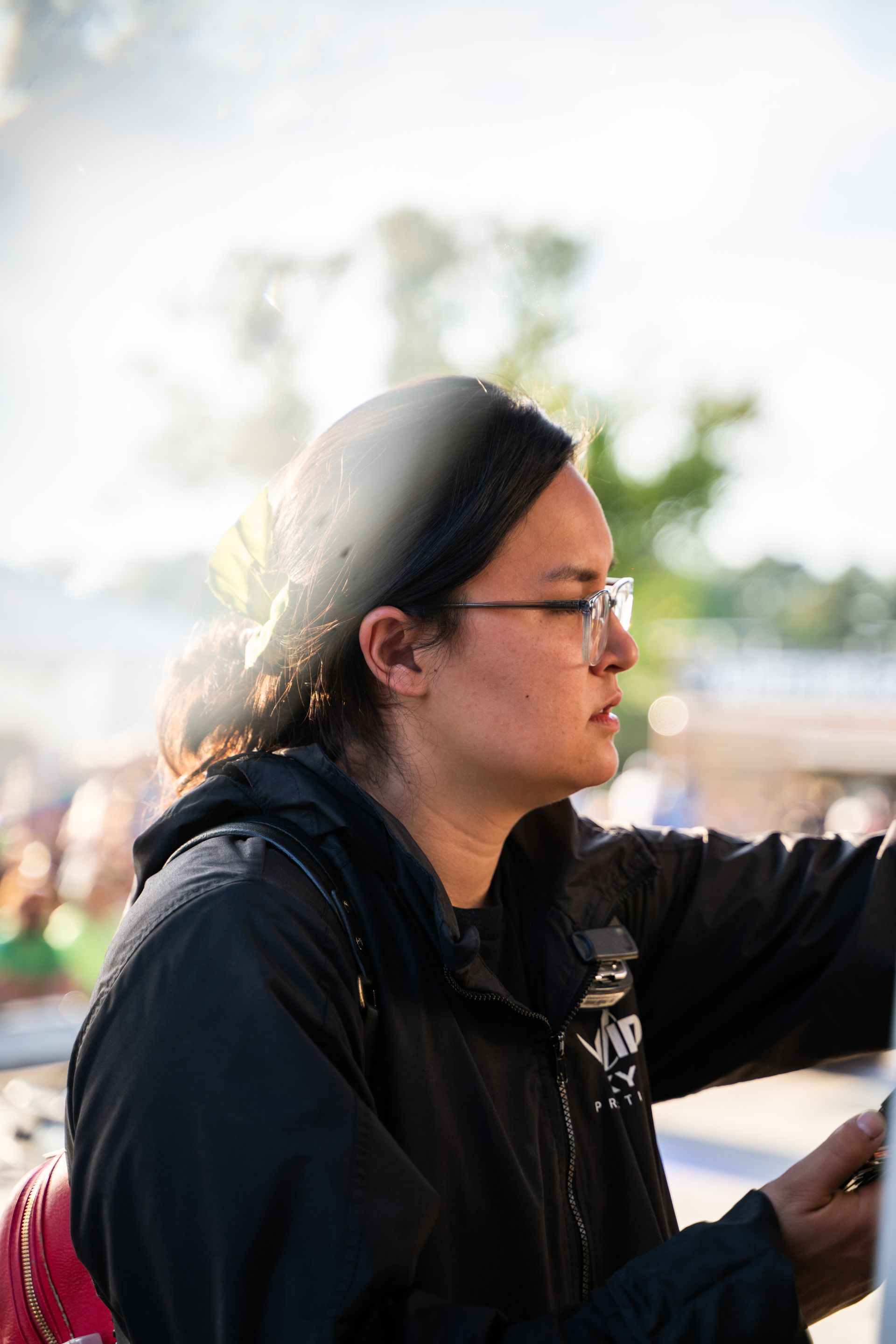A woman wearing glasses and a headband is looking at her phone.